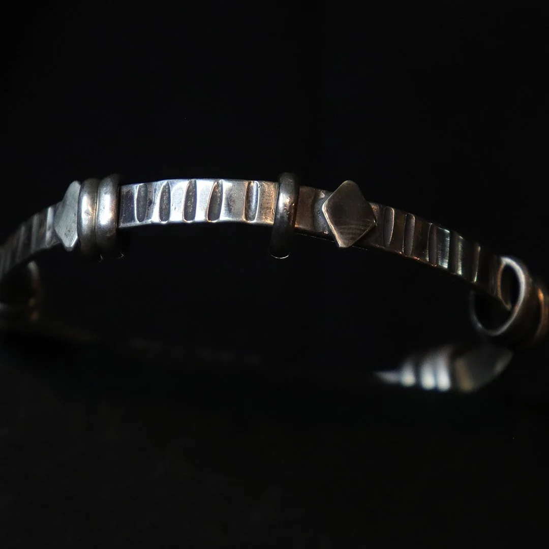 Sculptural sterling silver bangle with sliding rings and subtle texture