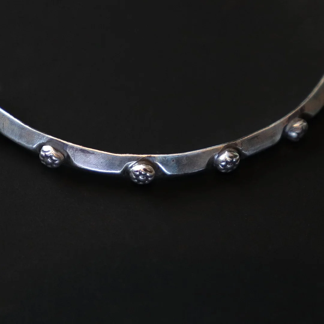 Minimalist sterling silver bangle featuring sculpted flower details