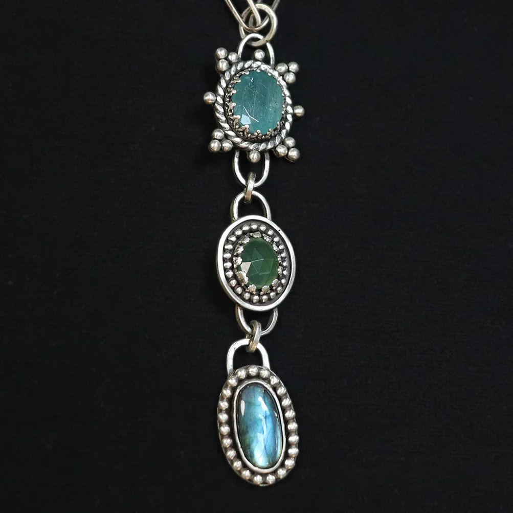 Handcrafted sterling silver pendant with grandidierite, serpentine, and labradorite stones in a vertical arrangement