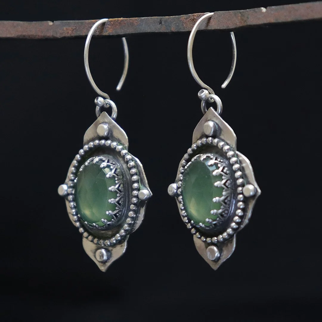Artisan silver earrings featuring oval serpentine stone with decorative silver detailing