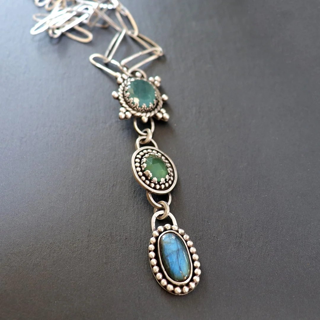 Sterling silver pendant with three gemstones including blue grandidierite, green serpentine, and iridescent labradorite