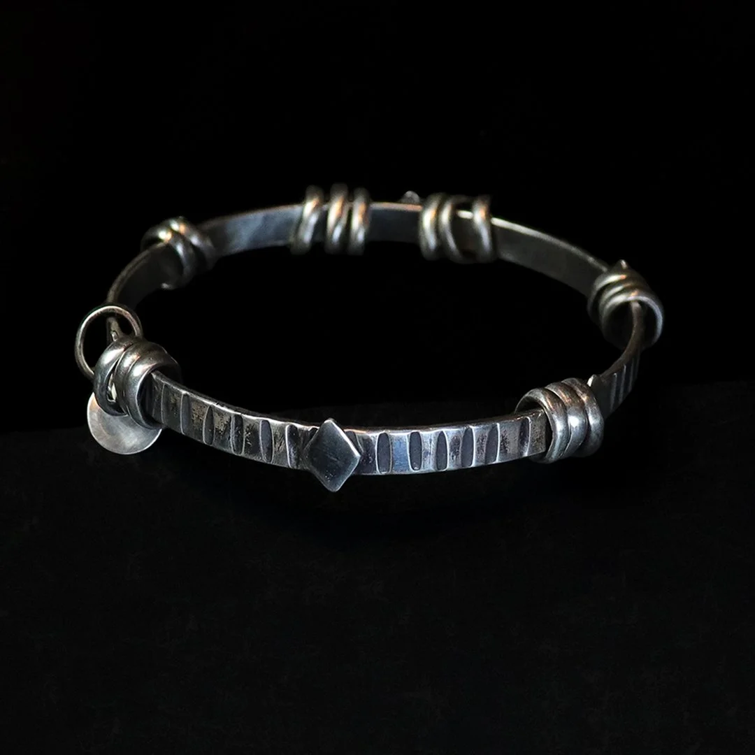 Handmade sterling silver bangle with movable rings and textured surface