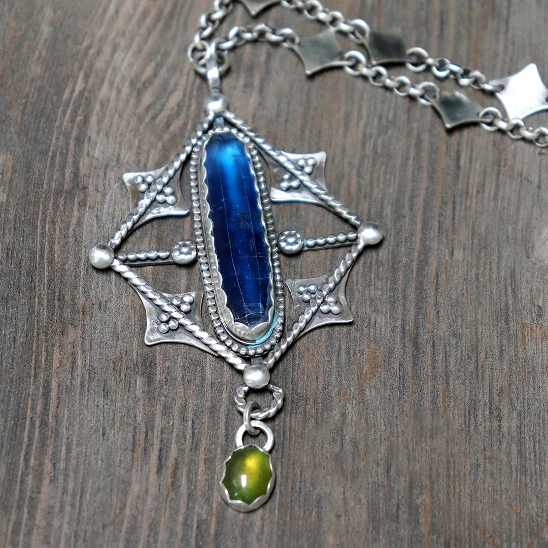 kite motif silver pendant featuring polished kyanite and small green serpentine stone