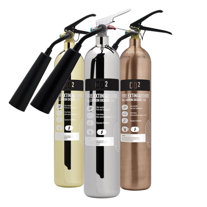 Three fire extinguishers labeled with CO2, containing carbon dioxide, displayed side by side in different colors: yellow, silver, and bronze.