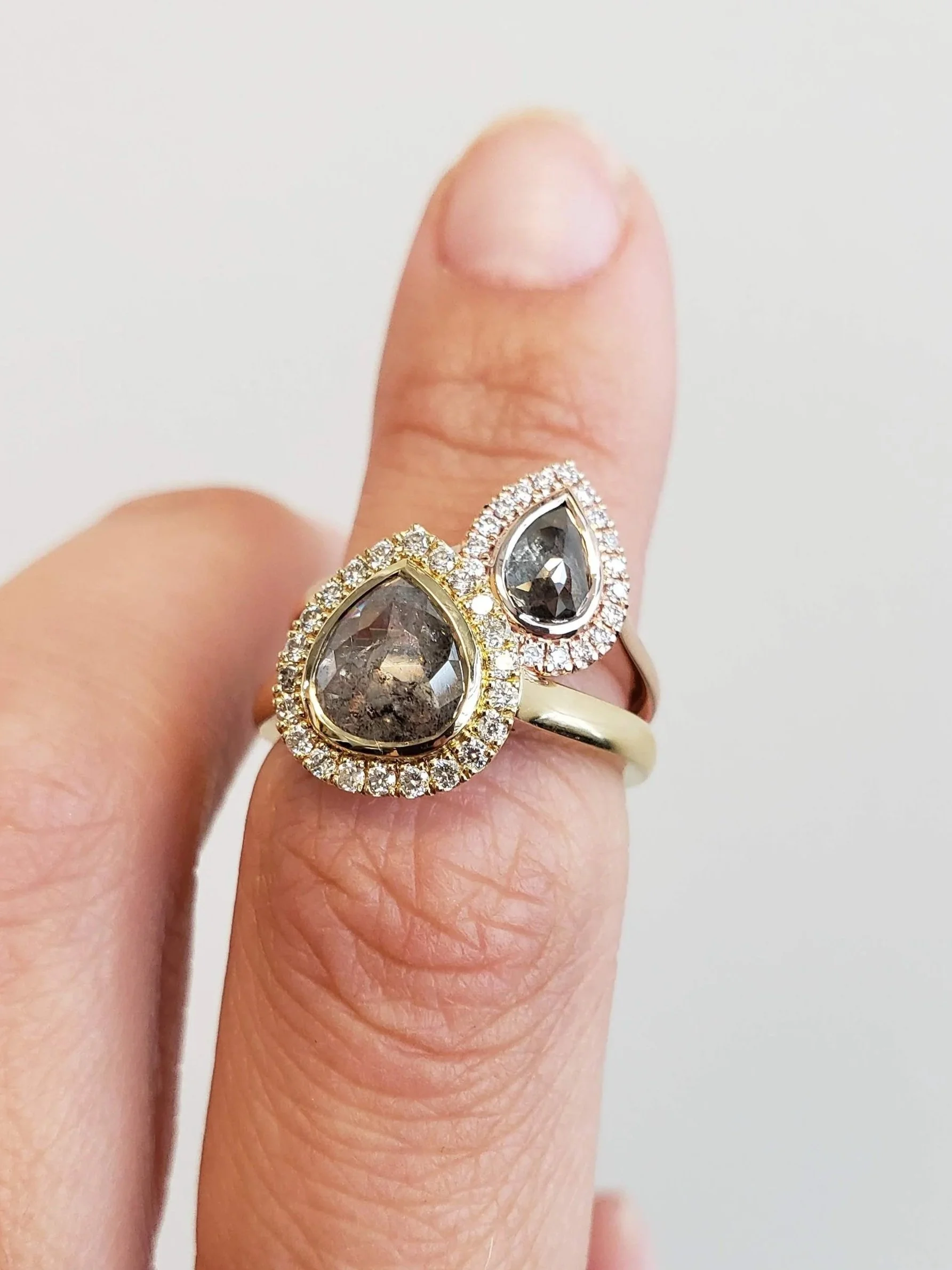 Pear shaped salt and pepper diamonds set into halo engagement ring settings