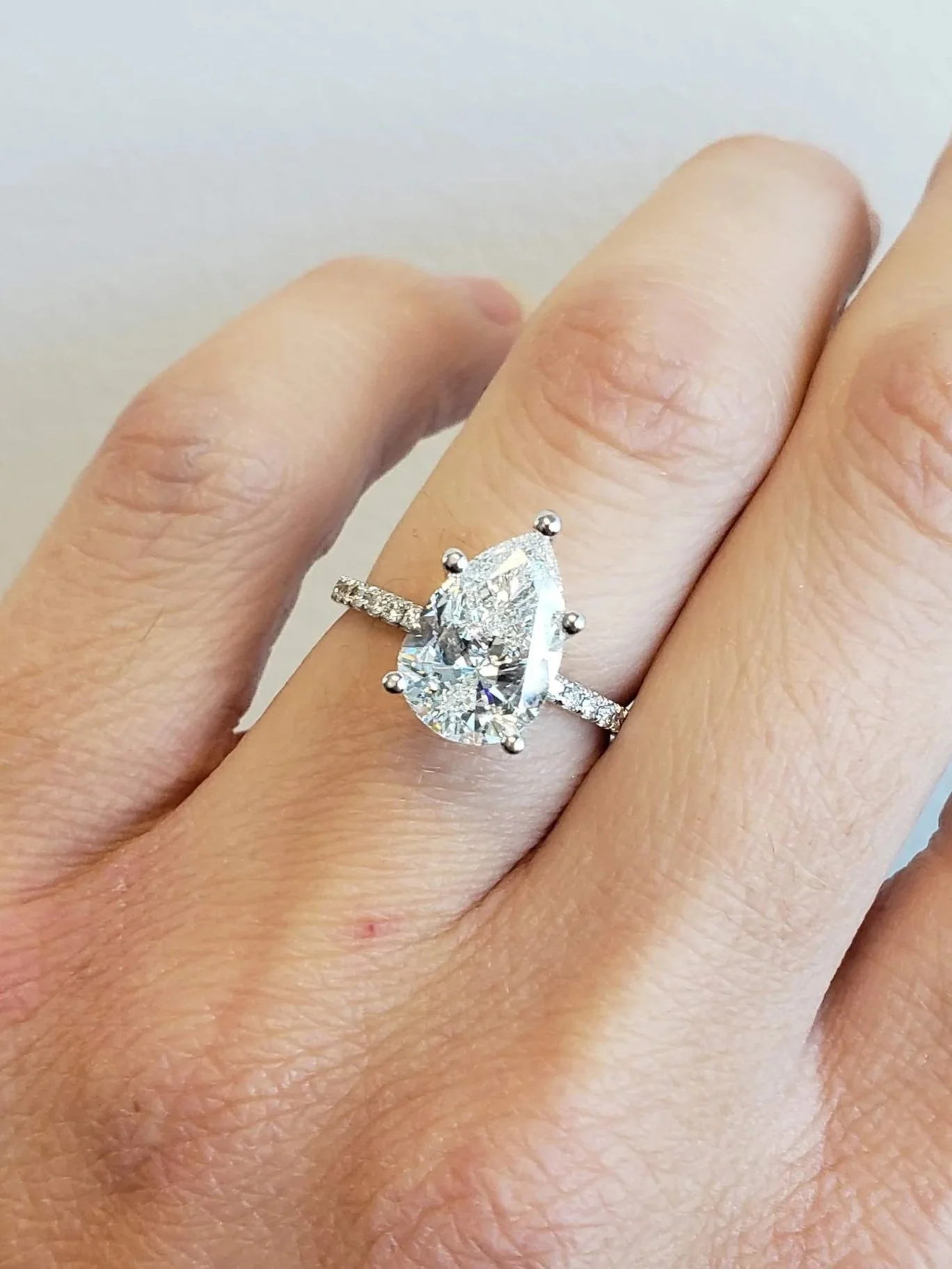 Pear shaped diamond engagement ring with micro pave diamond band