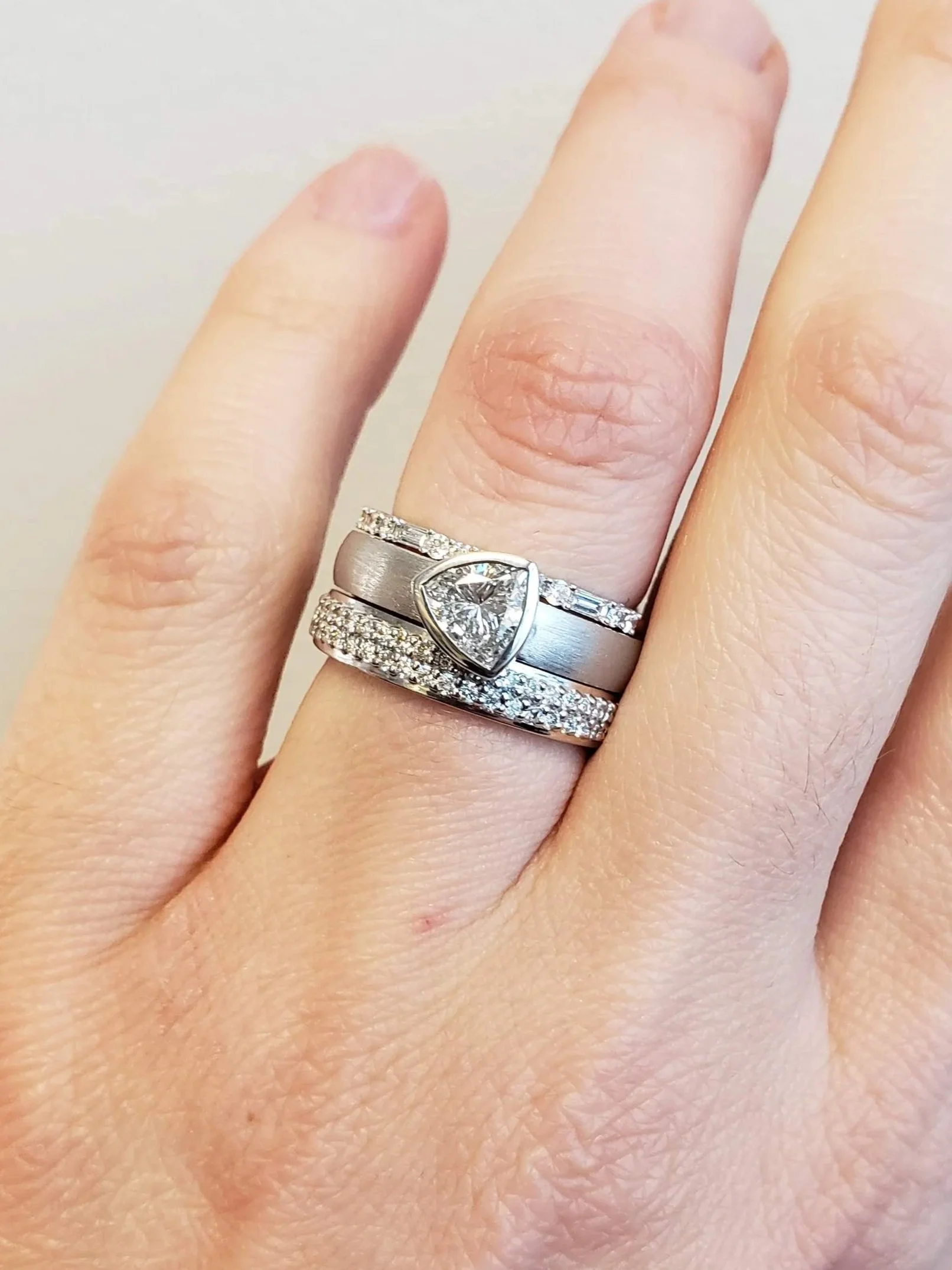 Trillon cut diamond bezel set into 19K white gold, pave and micro pave bands on either side