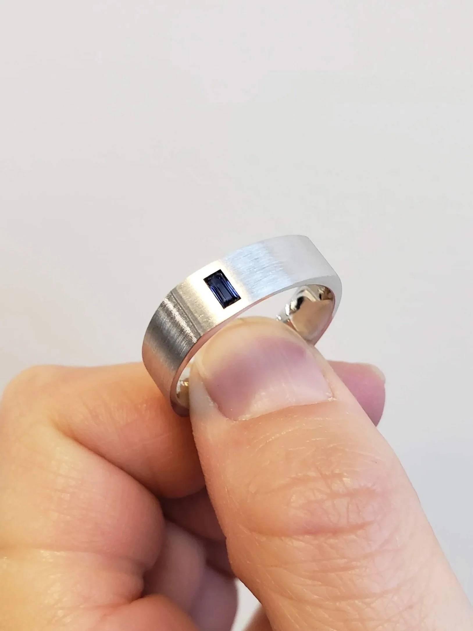 Men's white gold wedding band with gypsy set blue sapphire accent