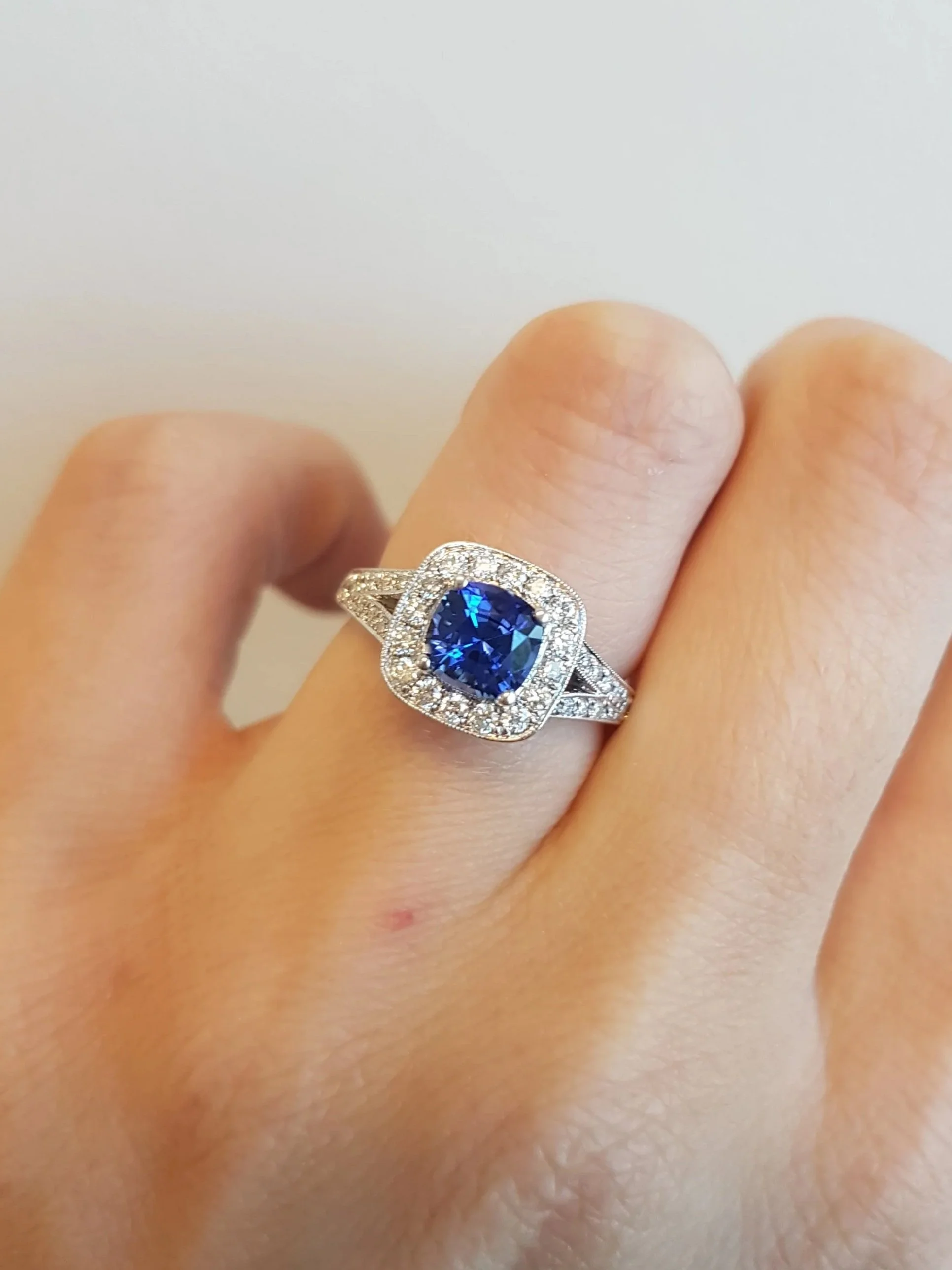 Blue sapphire halo engagement ring with split shank, set in white gold