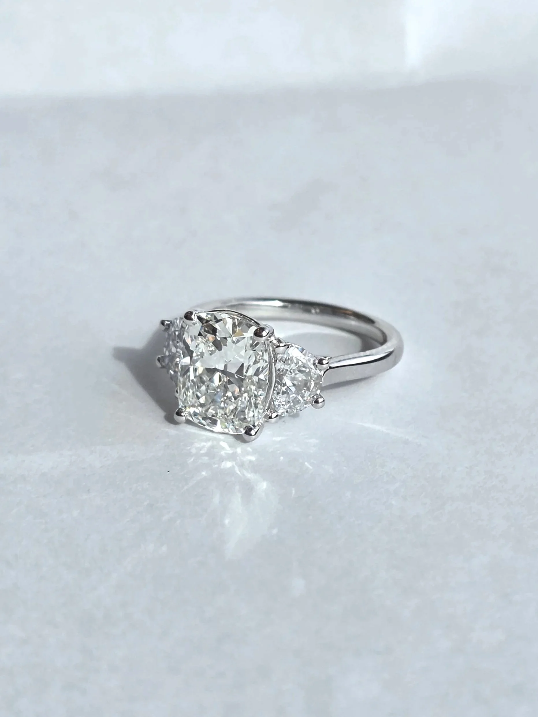 Custom elongated cushion three stone engagement ring with half moon accents