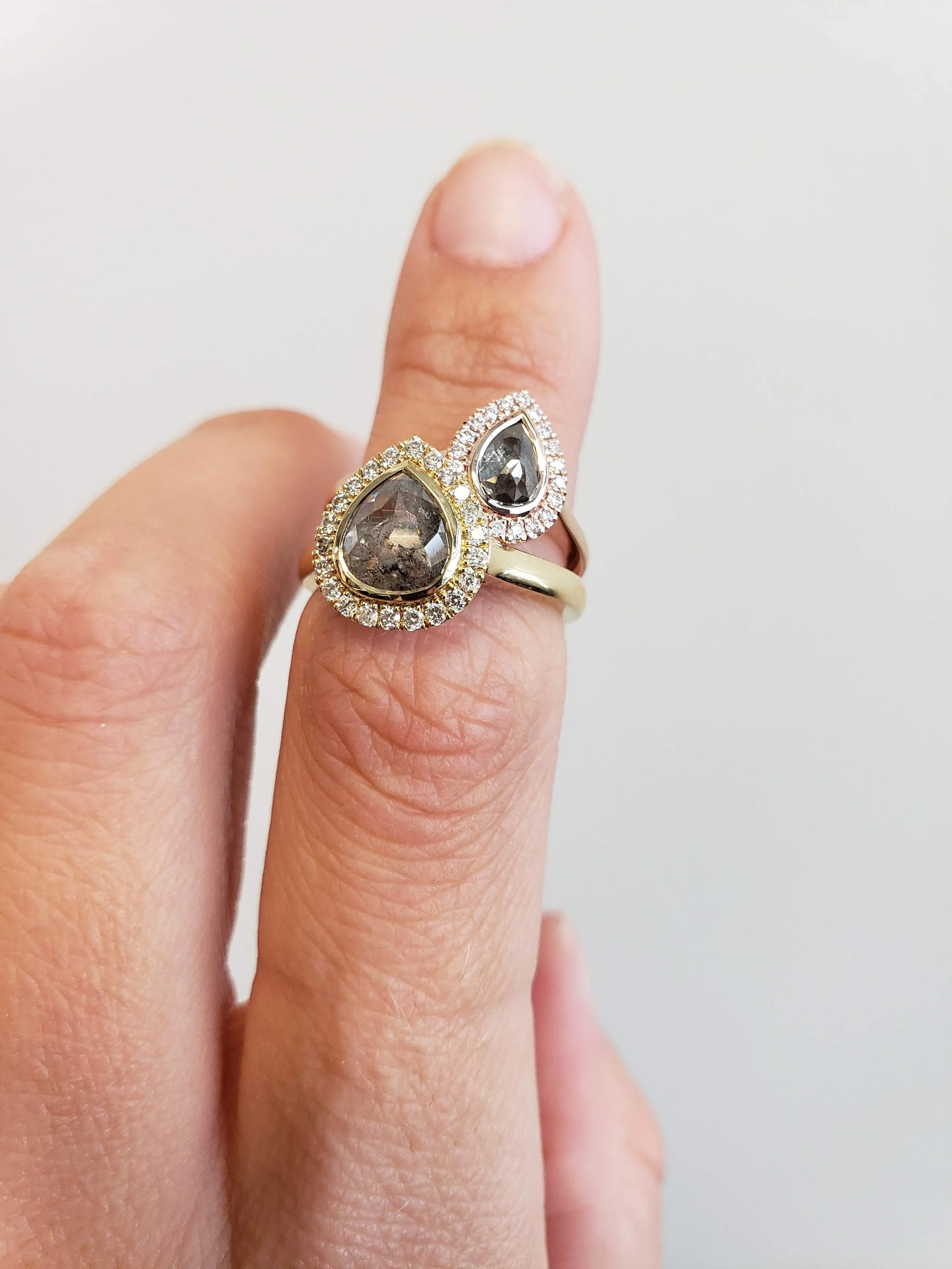 Pear shaped salt and pepper diamonds set into halo engagement ring settings