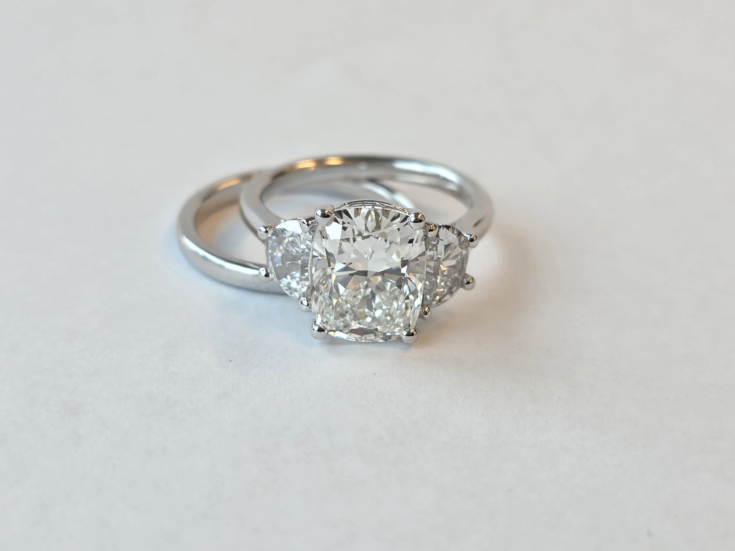 Custom elongated cushion three stone engagement ring with half moon accents
[engagement]