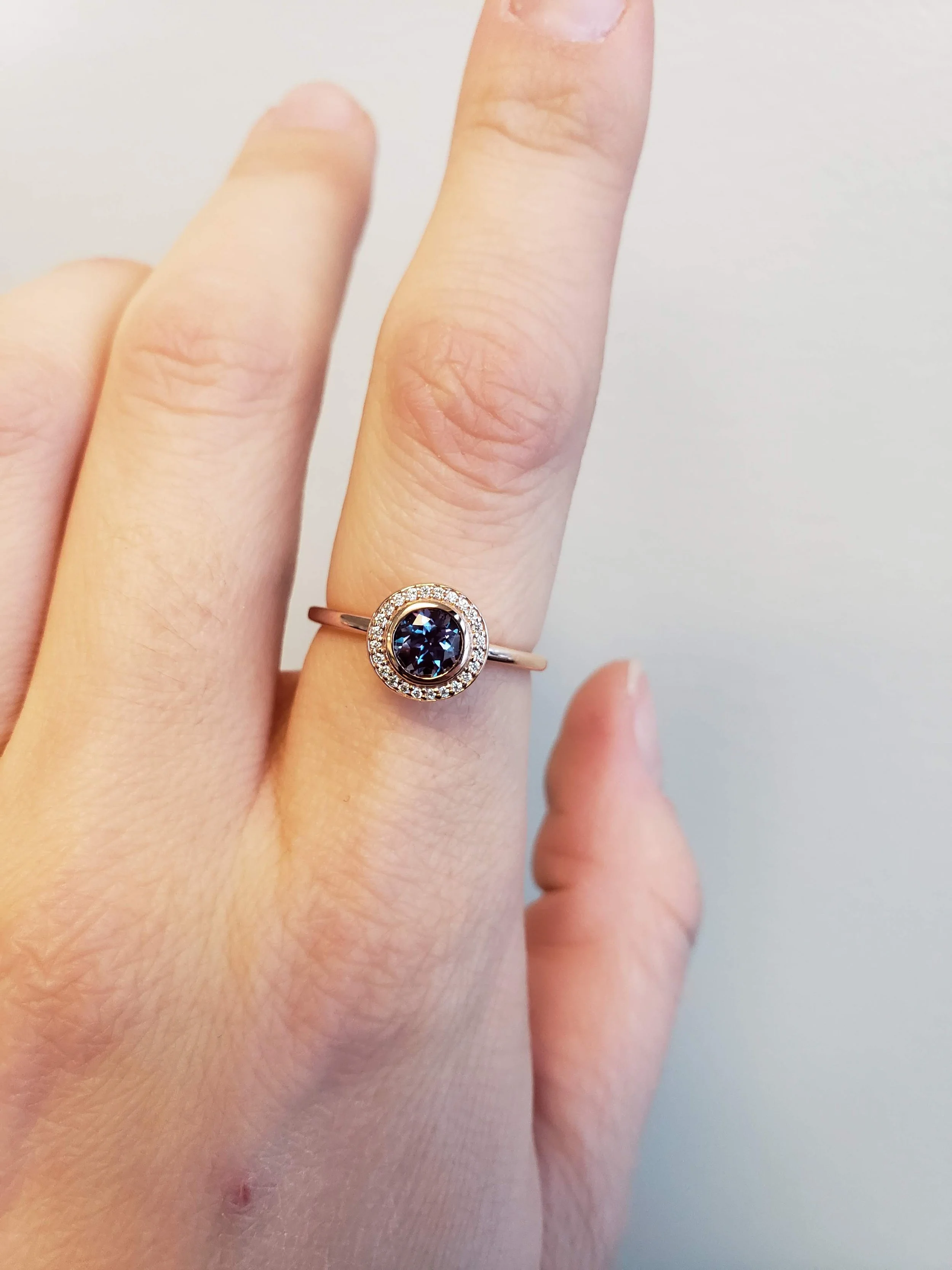 Alexandrite centre bezel set into rose gold halo engagement ring setting