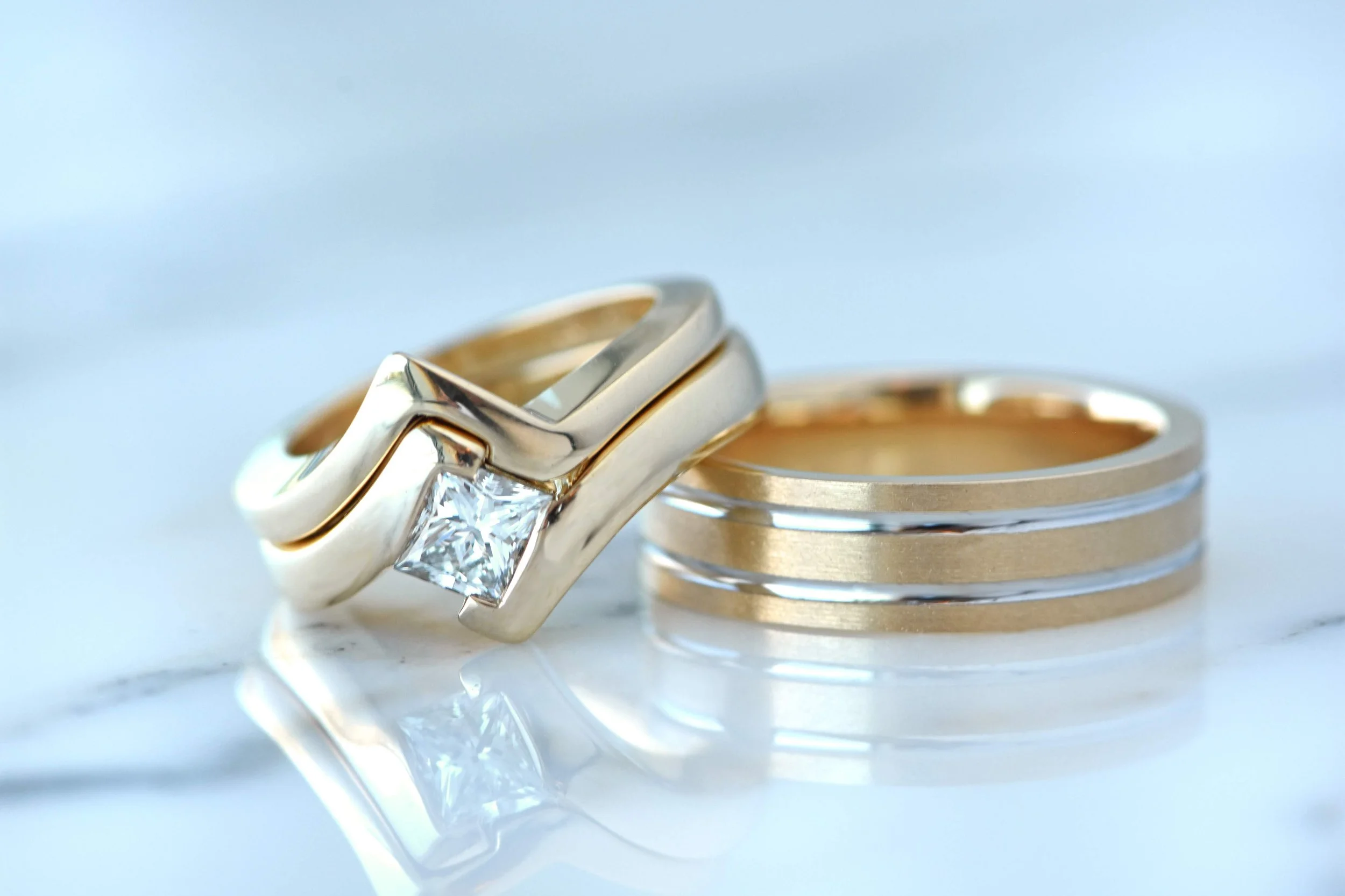 Custom his and hers wedding set in yellow gold with white gold accents. Engagement ring is a princess cut diamond set into a bypass style ring.