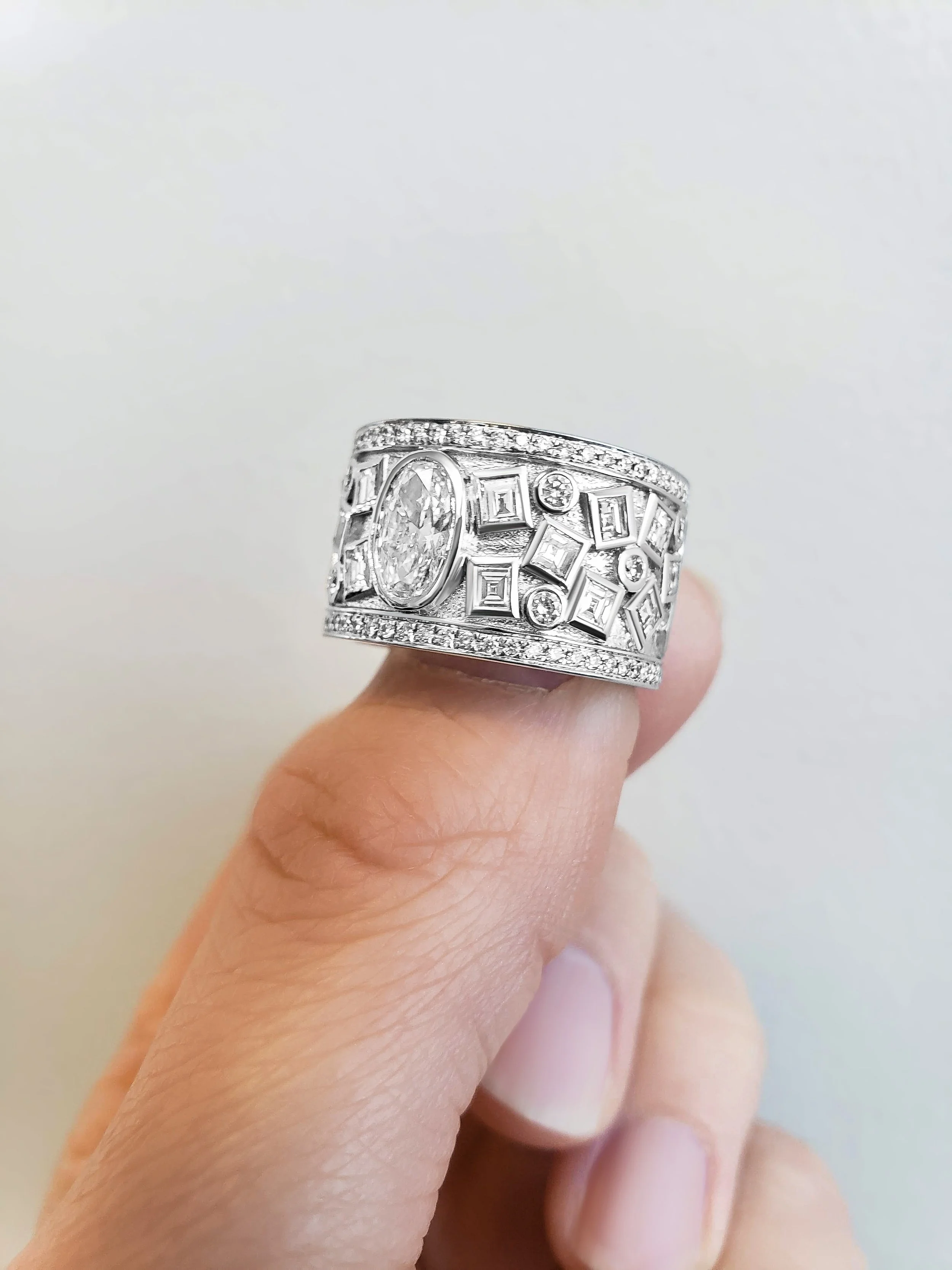 A silver ring with multiple small diamonds and a large oval diamond in center, set against a plain white background.