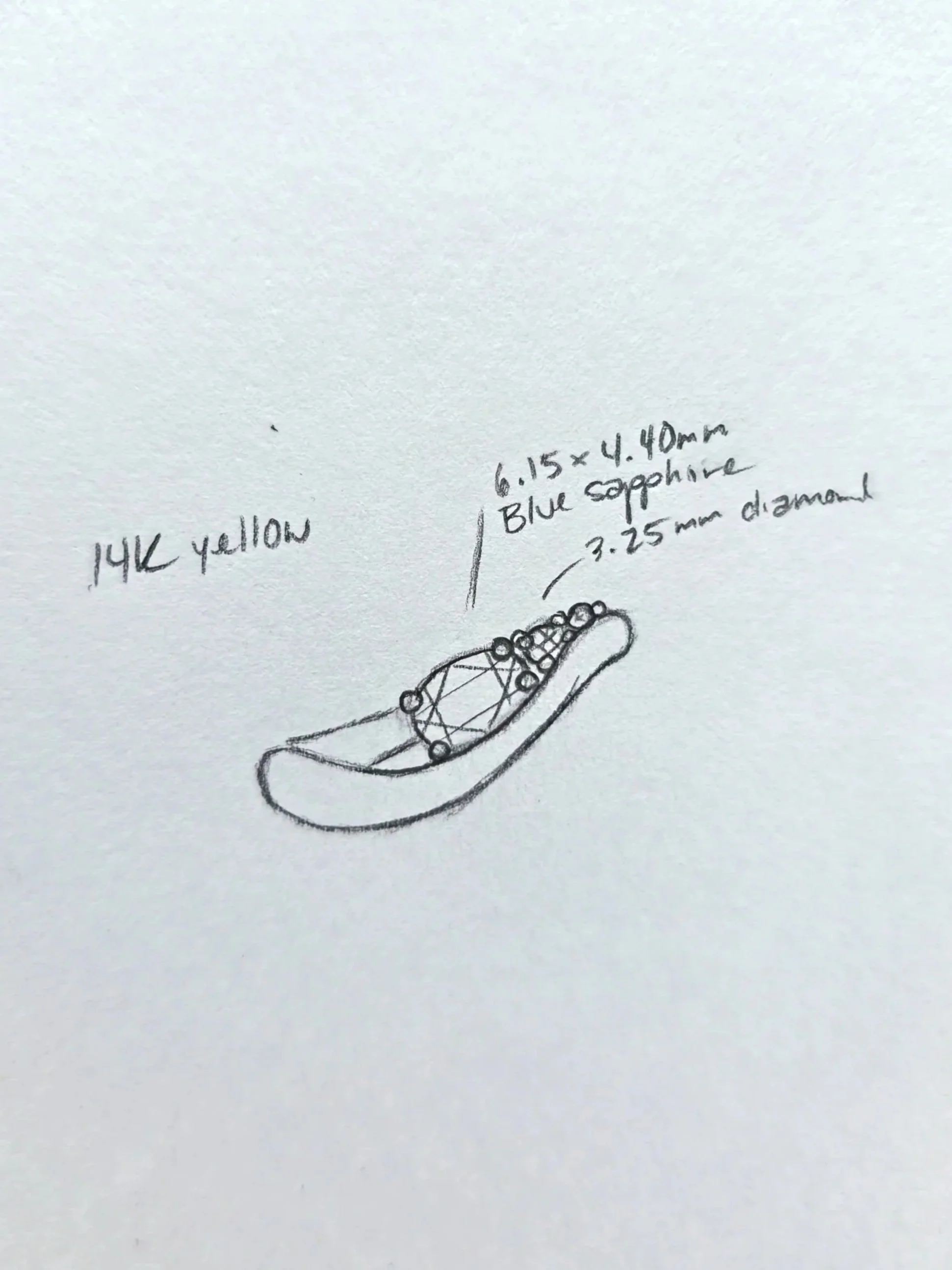 Hand-drawn sketch of a ring with notes about dimensions and materials, including a 14K yellow gold and blue sapphire details.