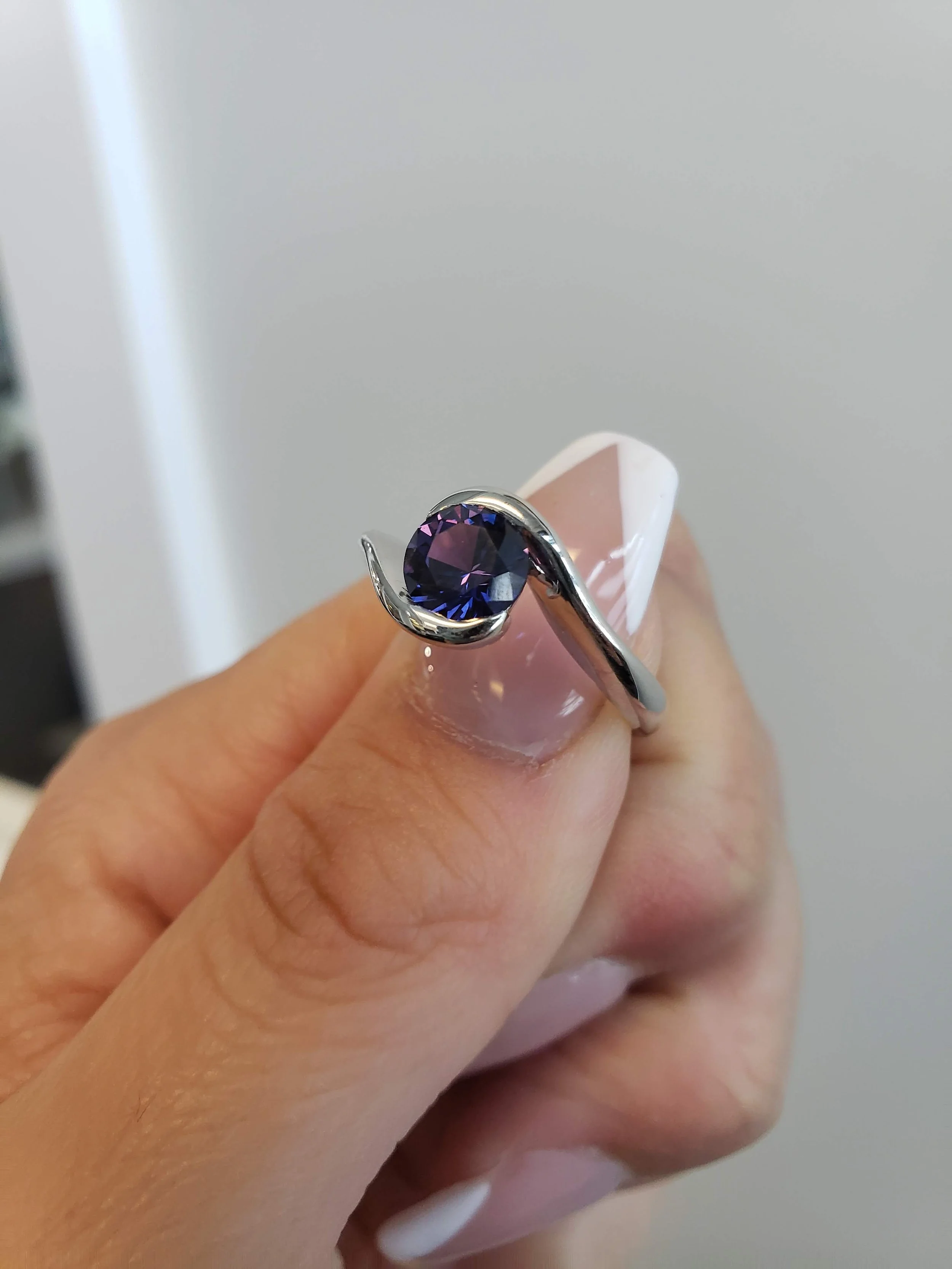 Bi-color blue-purple sapphire set into white gold bypass engagement ring