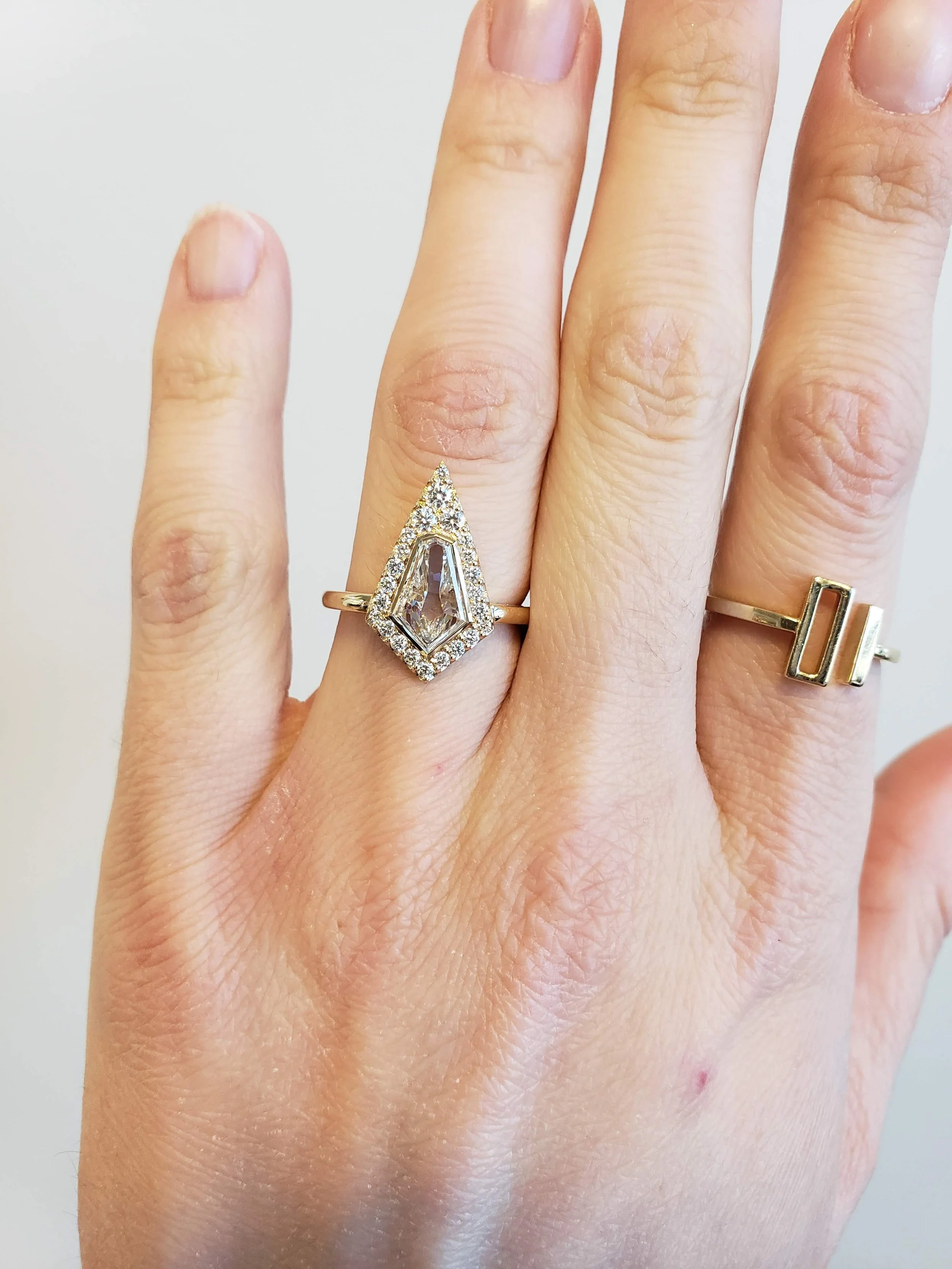 Kite shaped diamond engagement ring with pave set halo set in 14K yellow gold