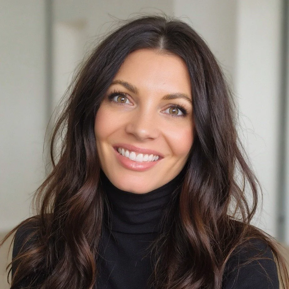 Close-up of a woman with long, wavy dark hair, wearing a black turtleneck, smiling at the camera.