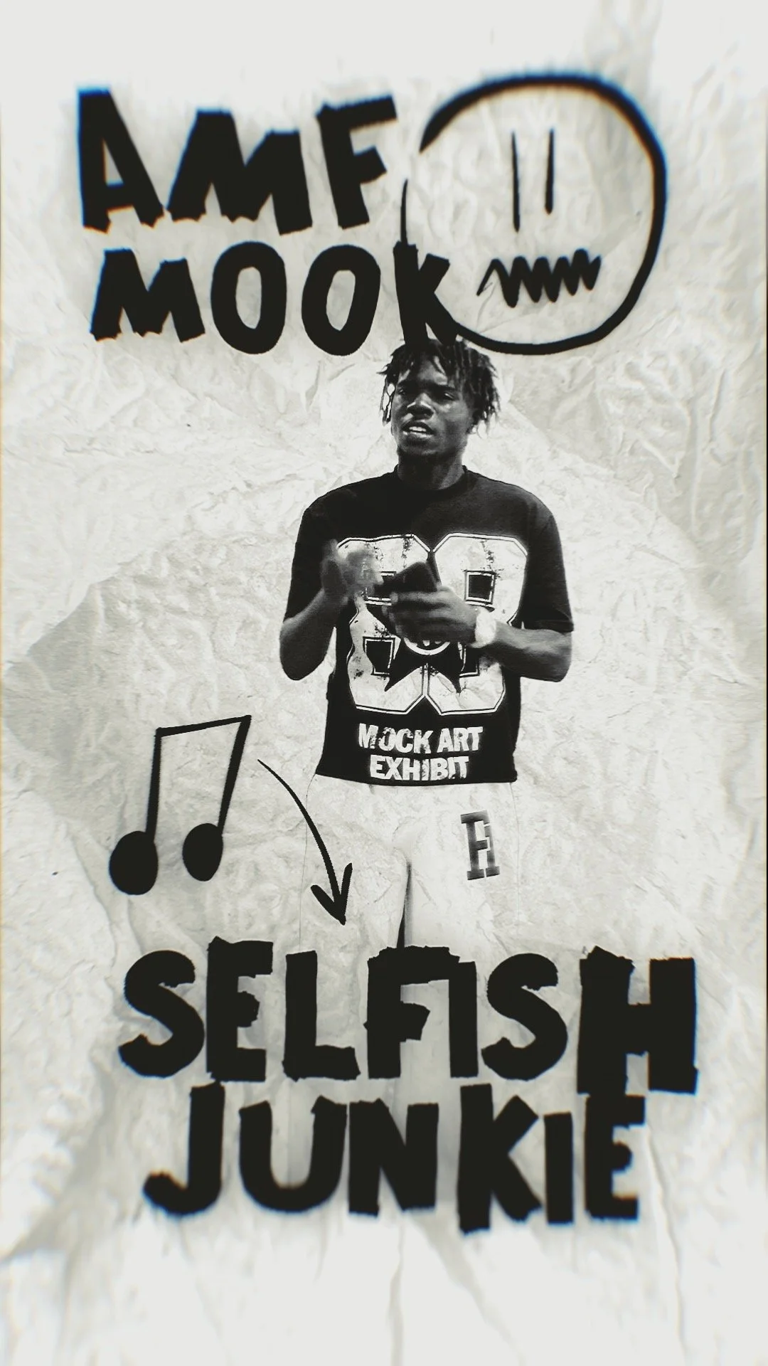 Black and white photo of a young man wearing a T-shirt that says 'Mock Art Exhibit' and pants with a letter 'F', standing in front of a textured wall with graffiti-style text and drawings, including the words 'AMF MOOK', a speech bubble, musical note