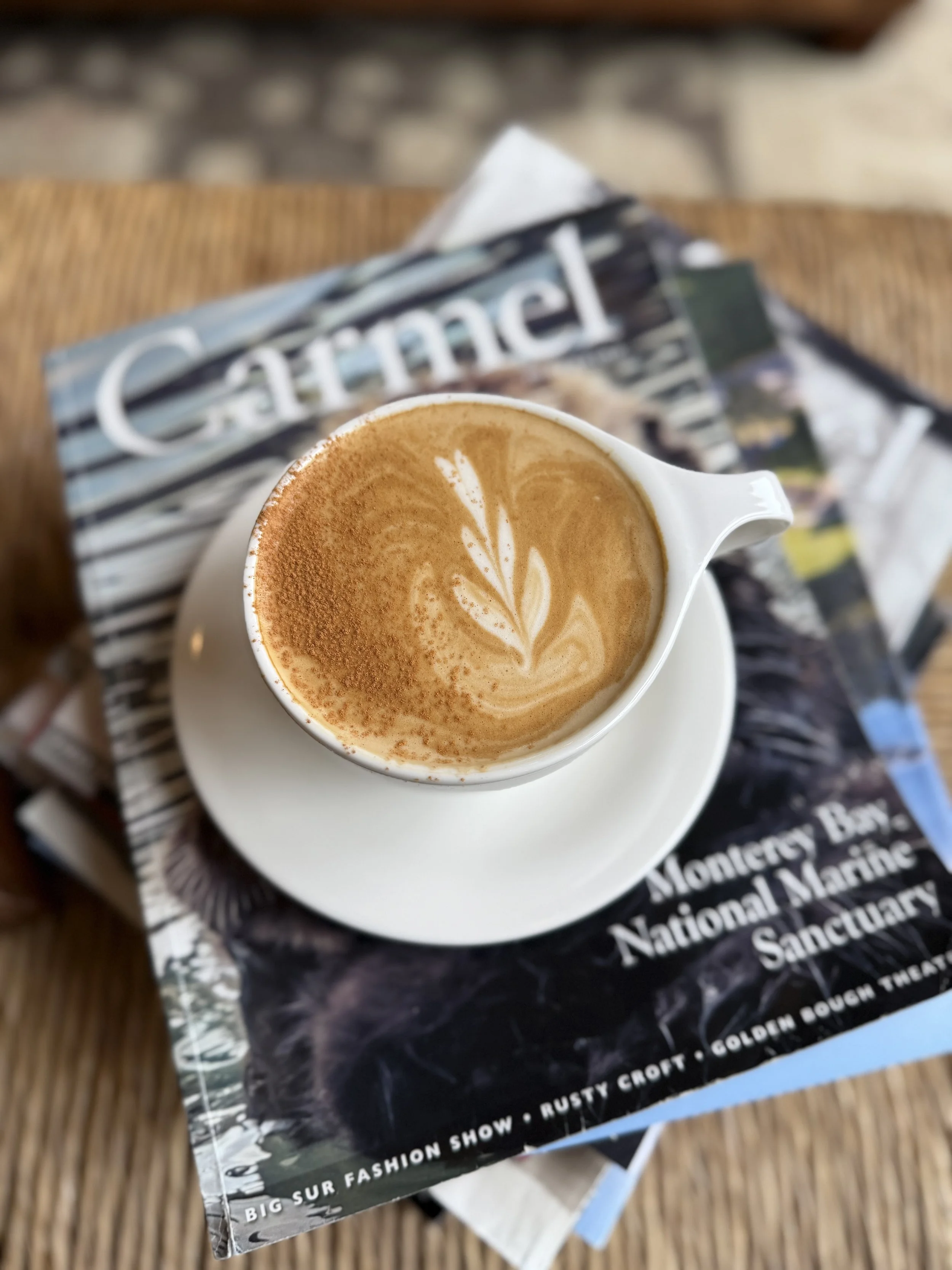 A cup of latte with latte art on top, placed on a magazine about the Monterey Bay National Marine Sanctuary.