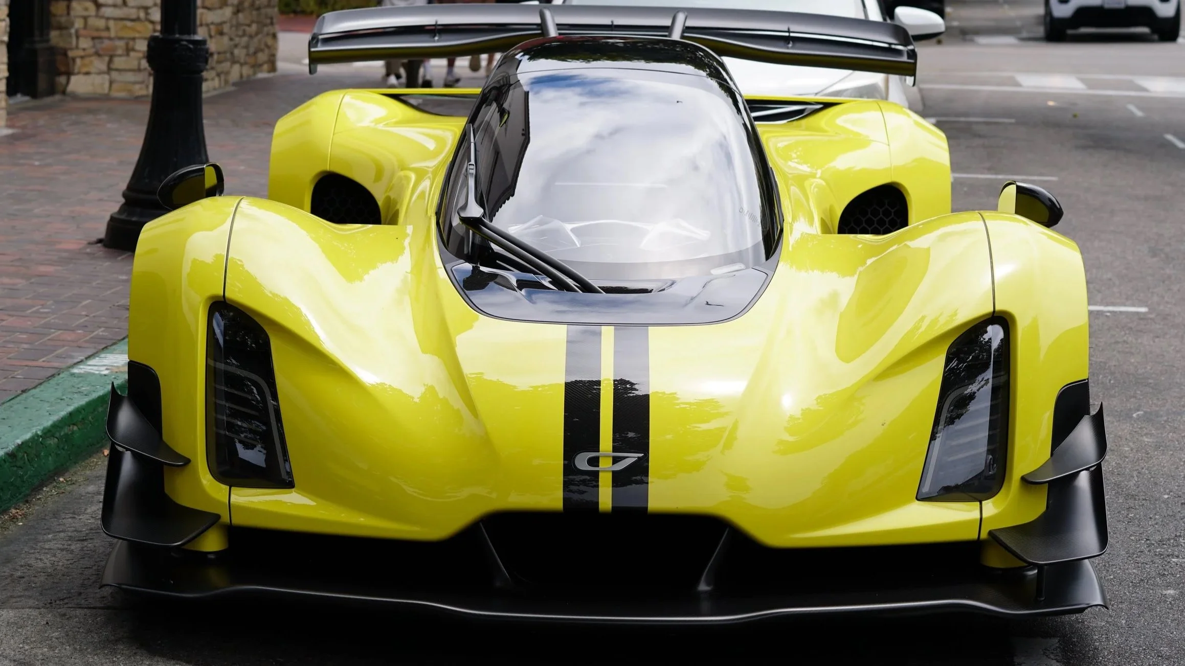 Yellow race car with black racing stripe parked in a parking lot.