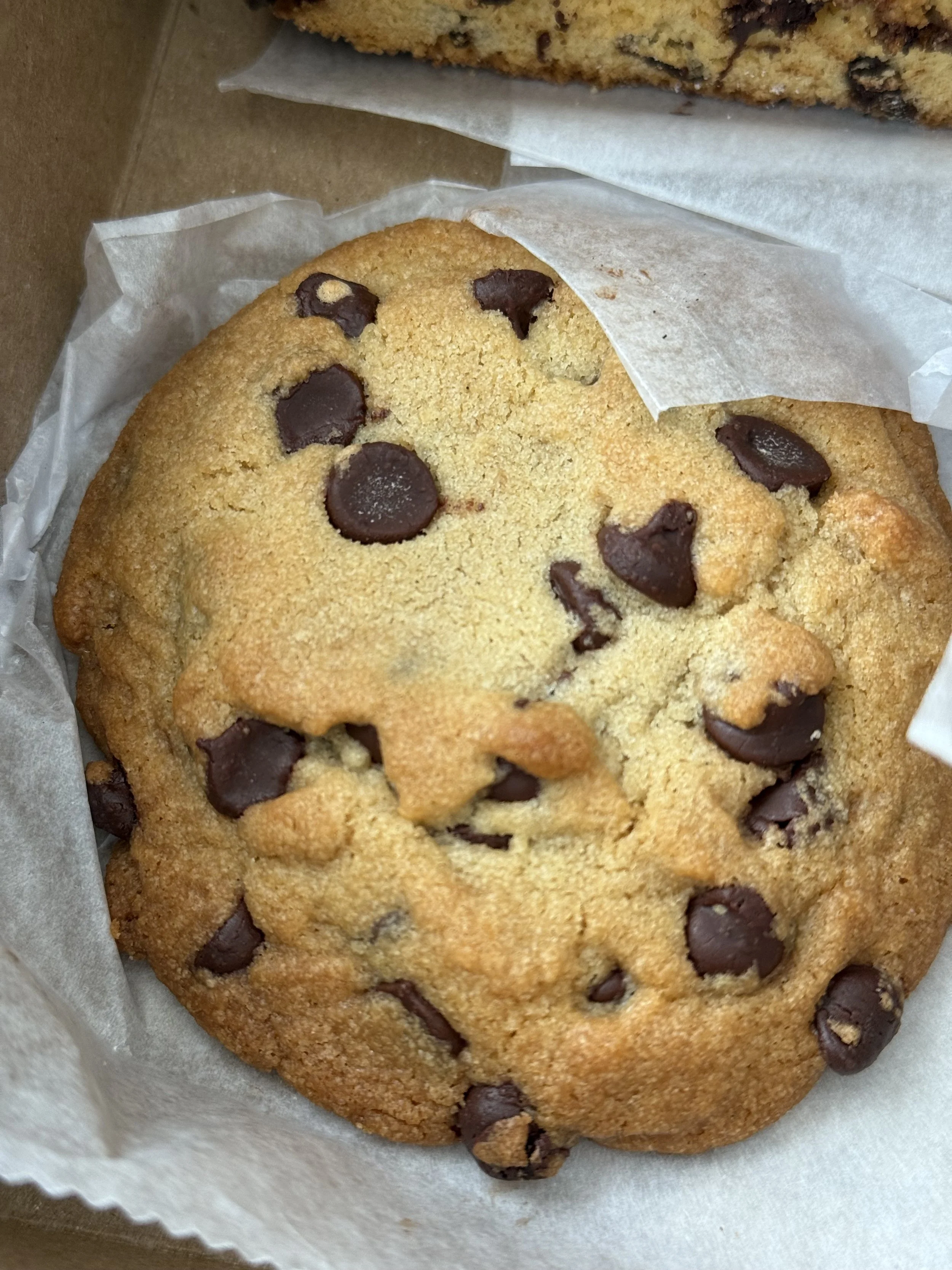 A chocolate chip cookie inside a paper-lined box.
