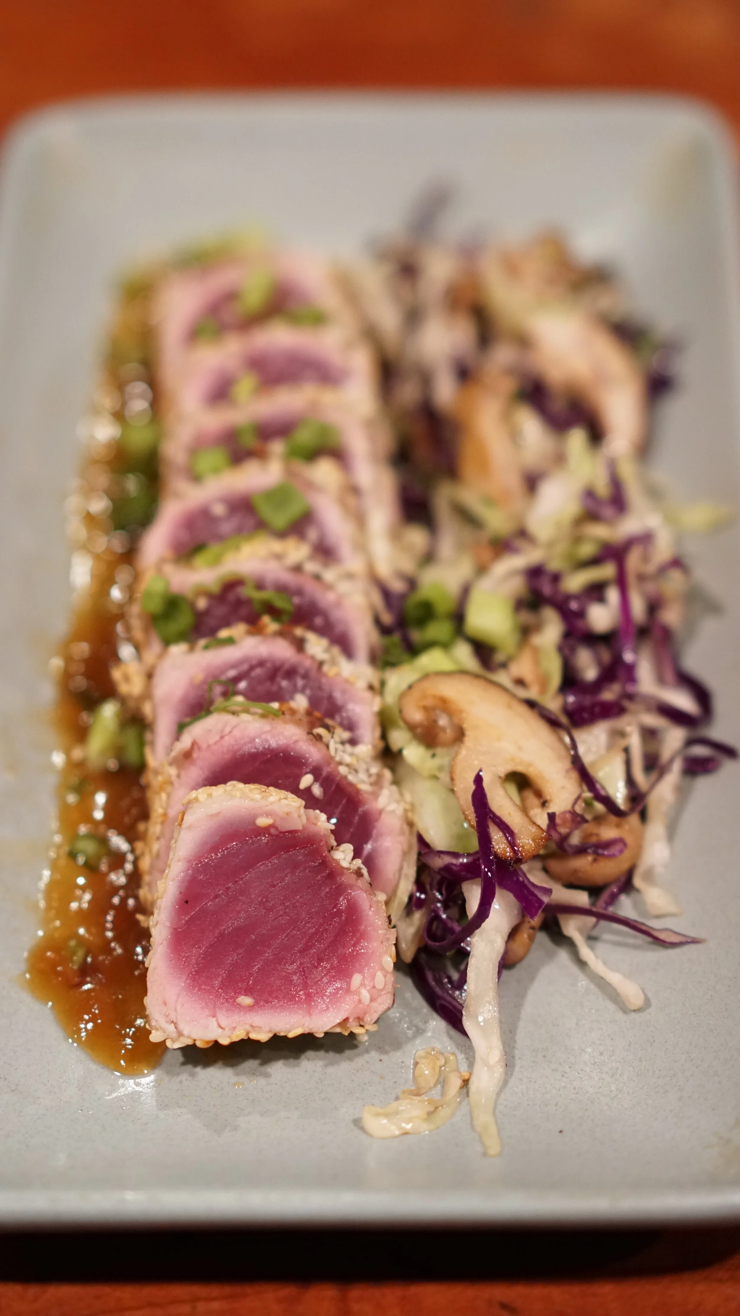 Seared ahi tuna sashimi with sesame seeds, served with shredded cabbage salad and a soy-based dipping sauce.