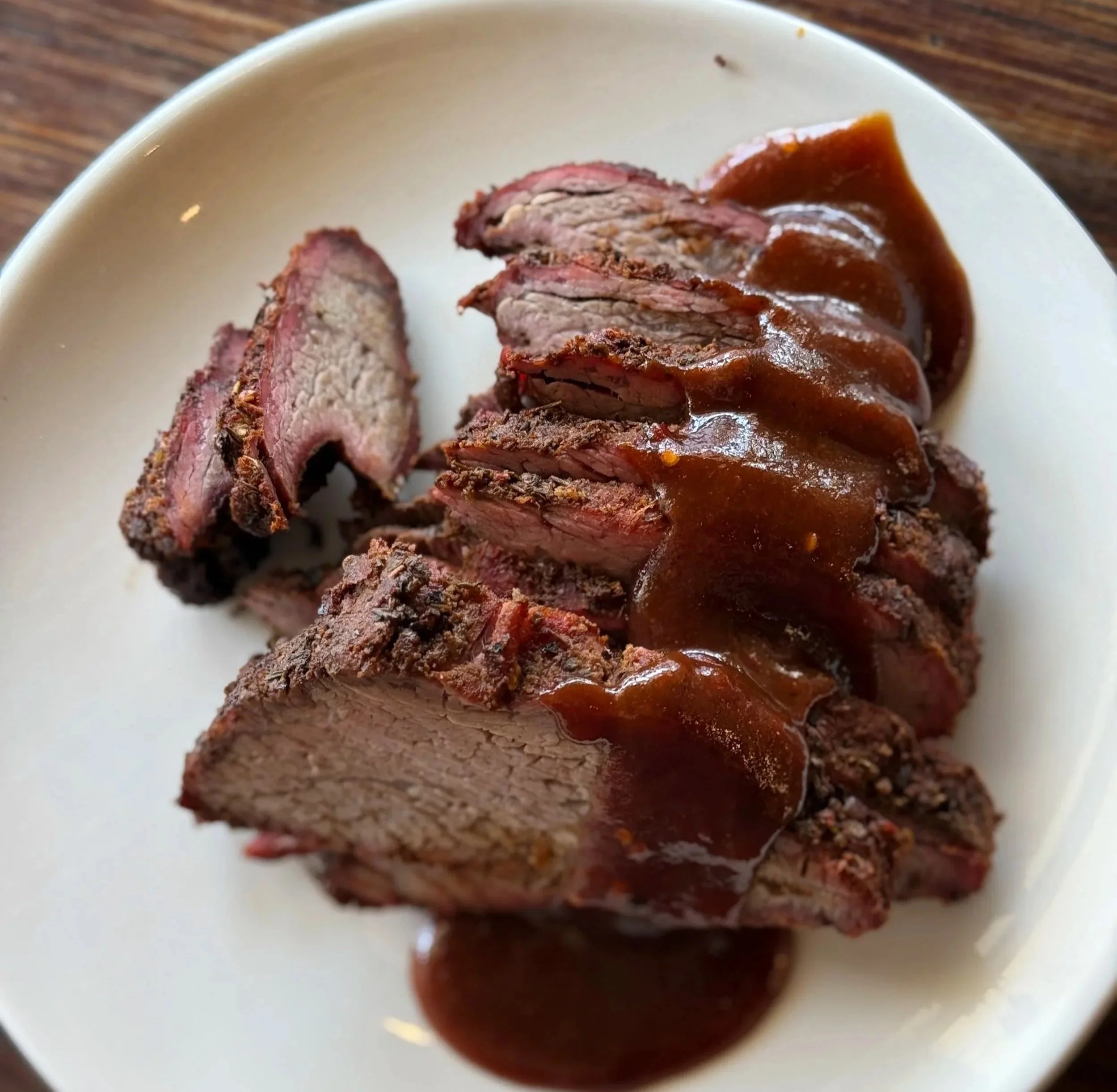 Slices of cooked beef steak with brown gravy on a white plate.