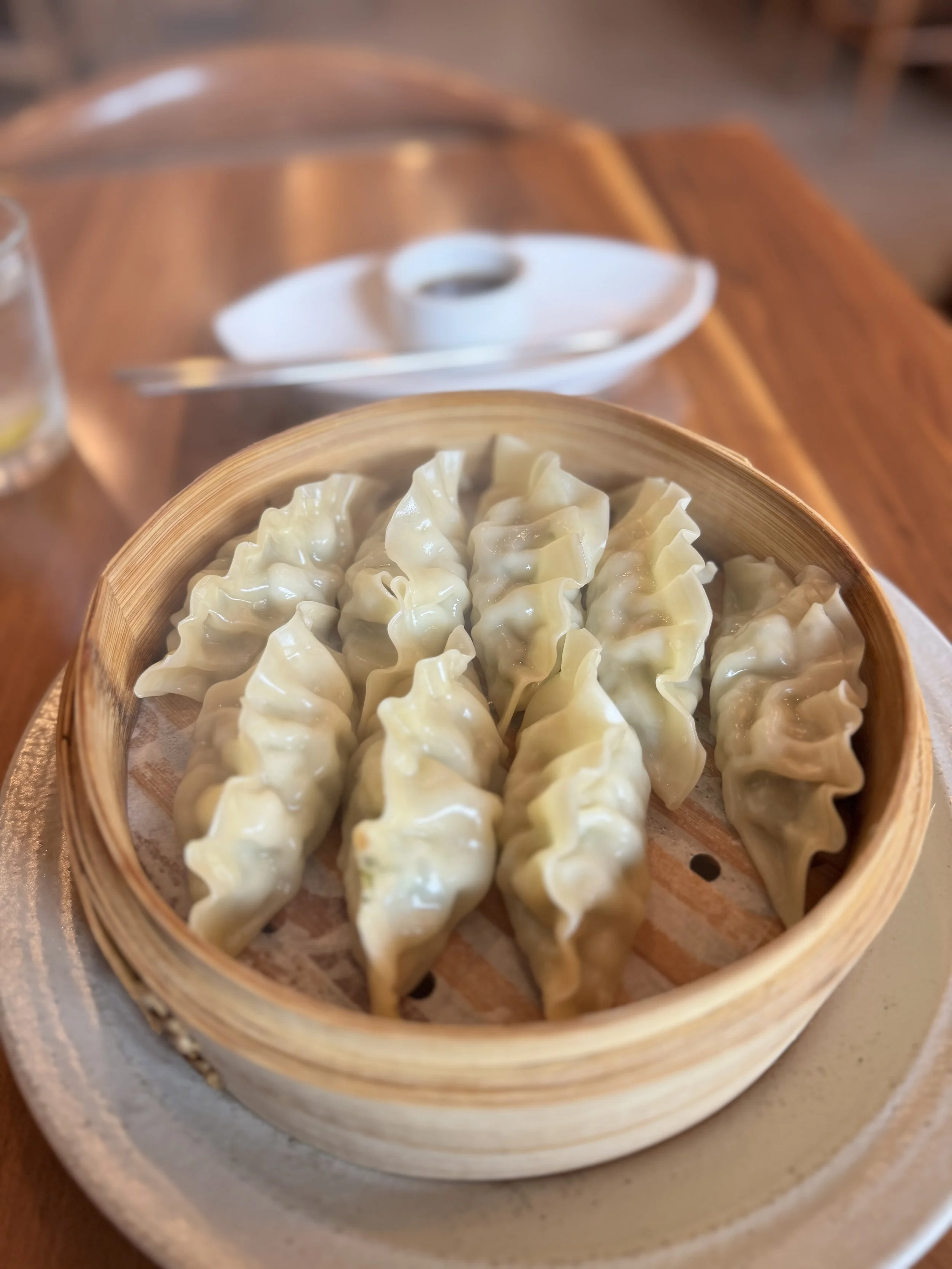 Steamed dumplings in a bamboo steamer basket on a table.