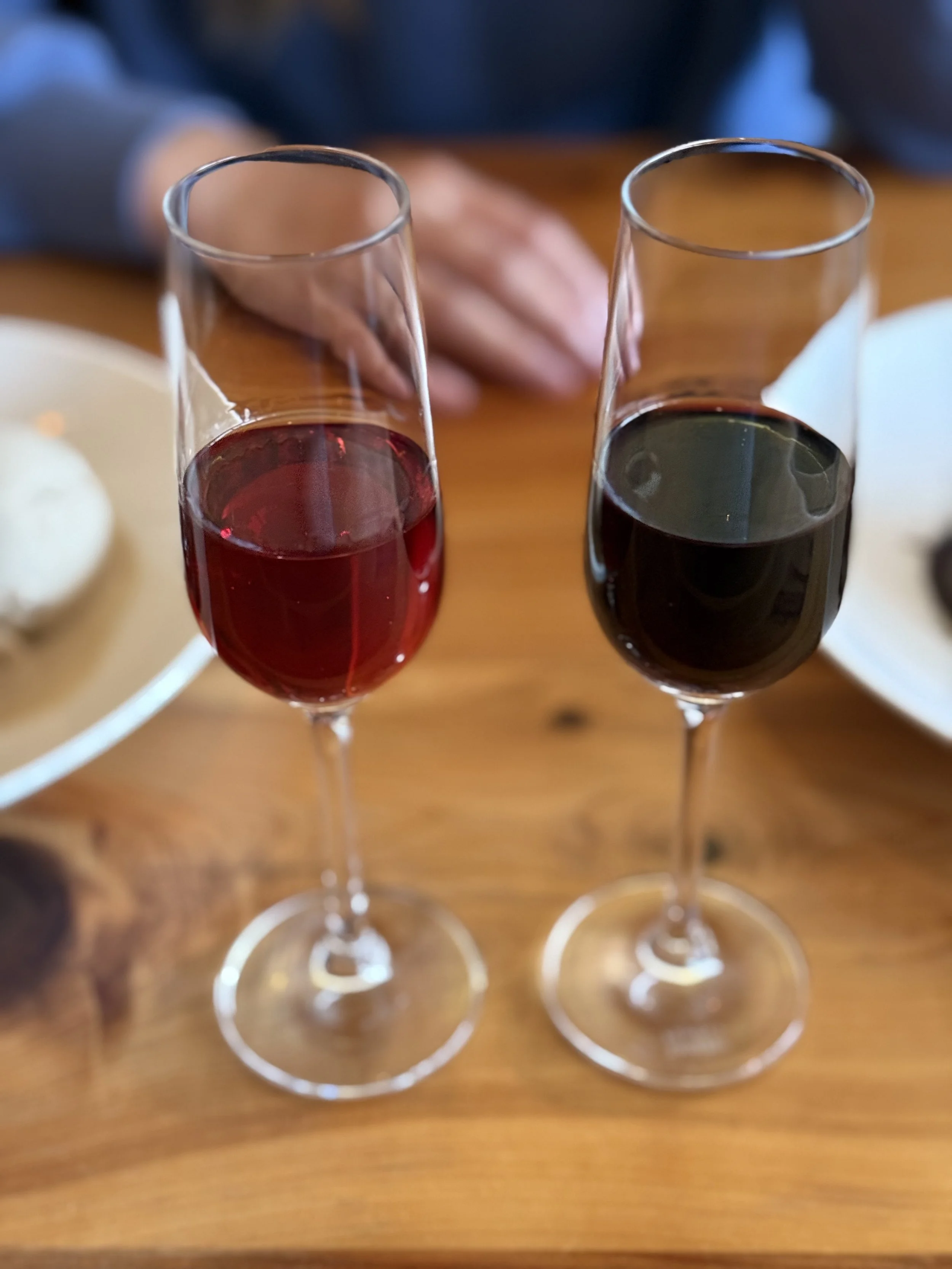 Two glasses of red and white wine on a wooden table.