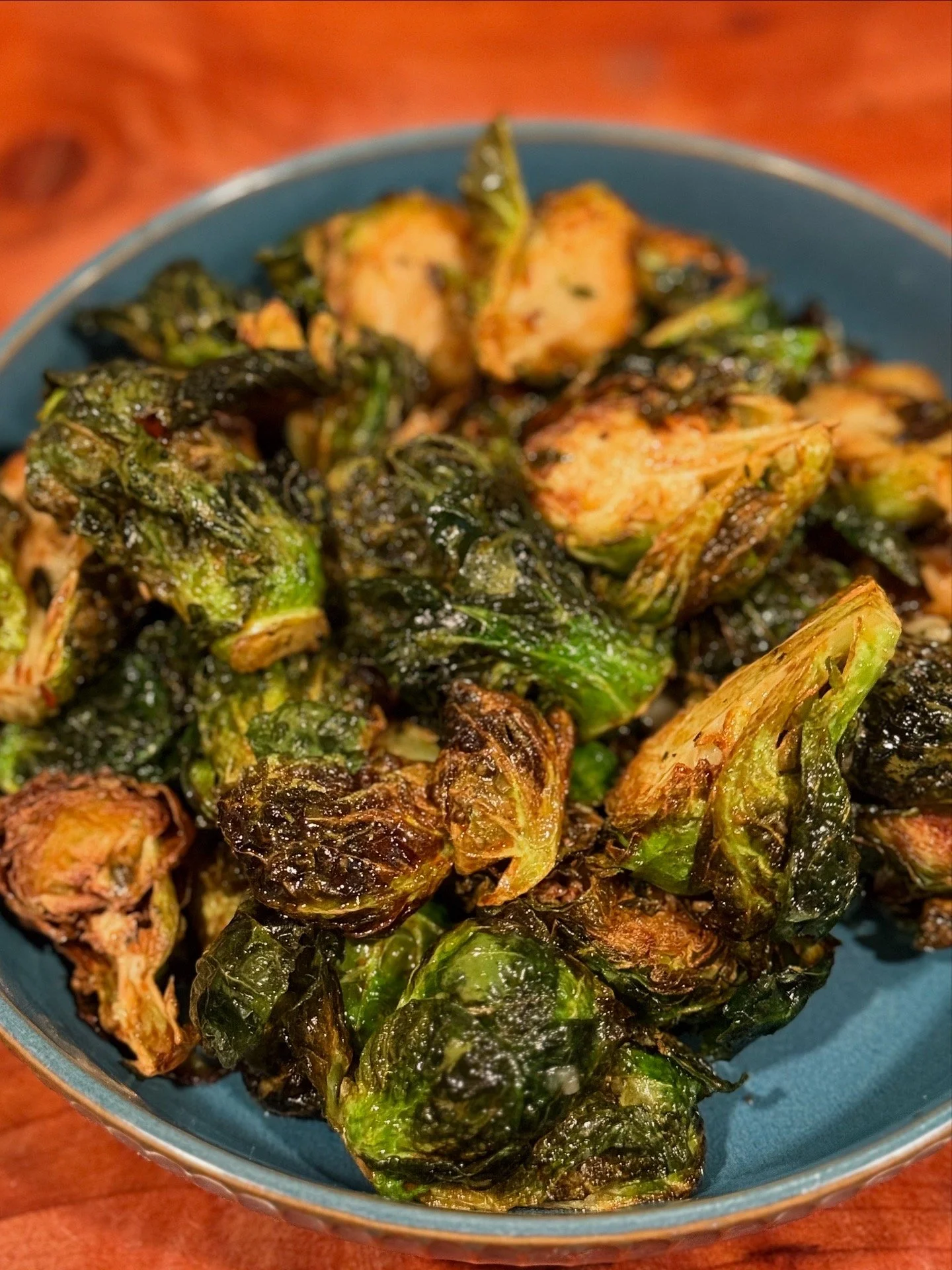 Roasted Brussels sprouts in a blue bowl on a wooden table.