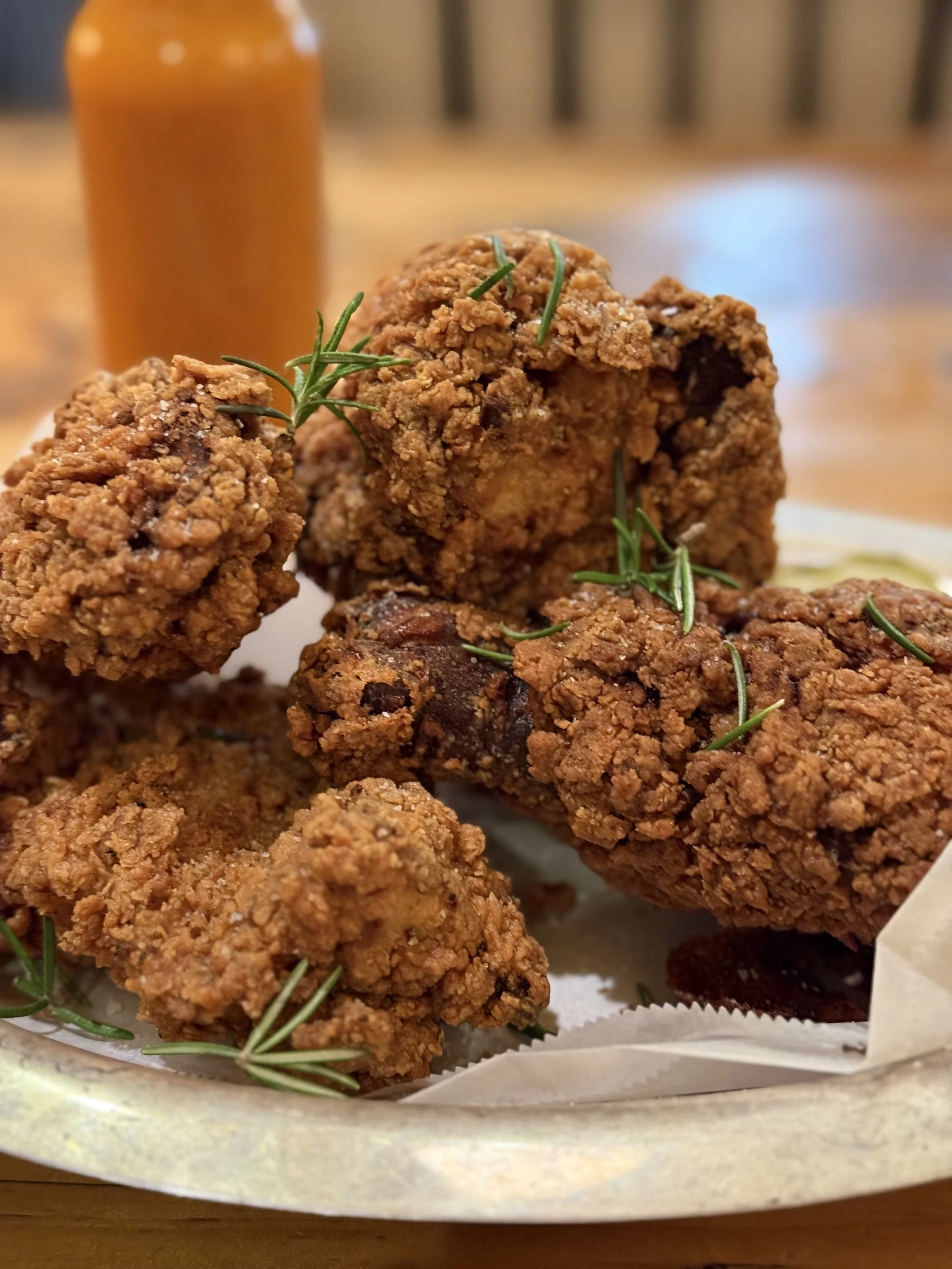 Close-up of fried chicken pieces garnished with rosemary on a tray.