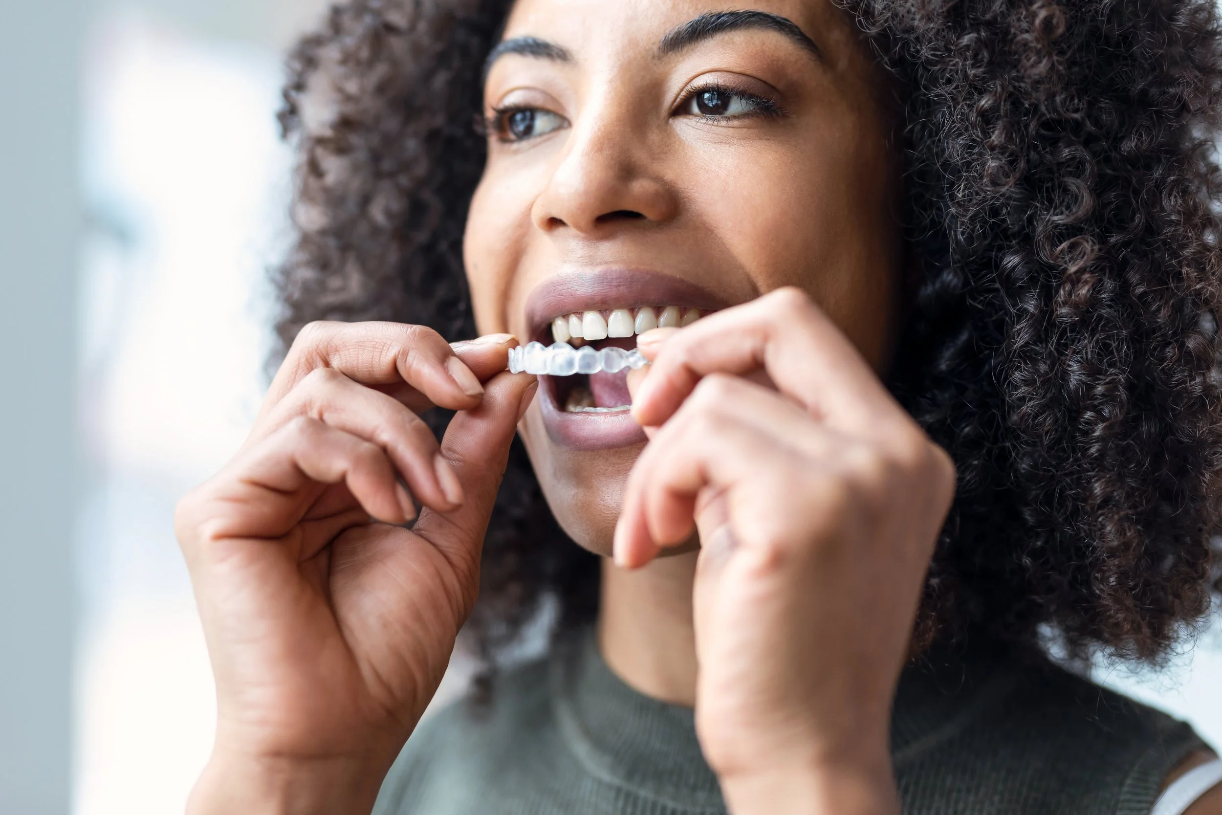 Woman putting Invisalign in her mouth.