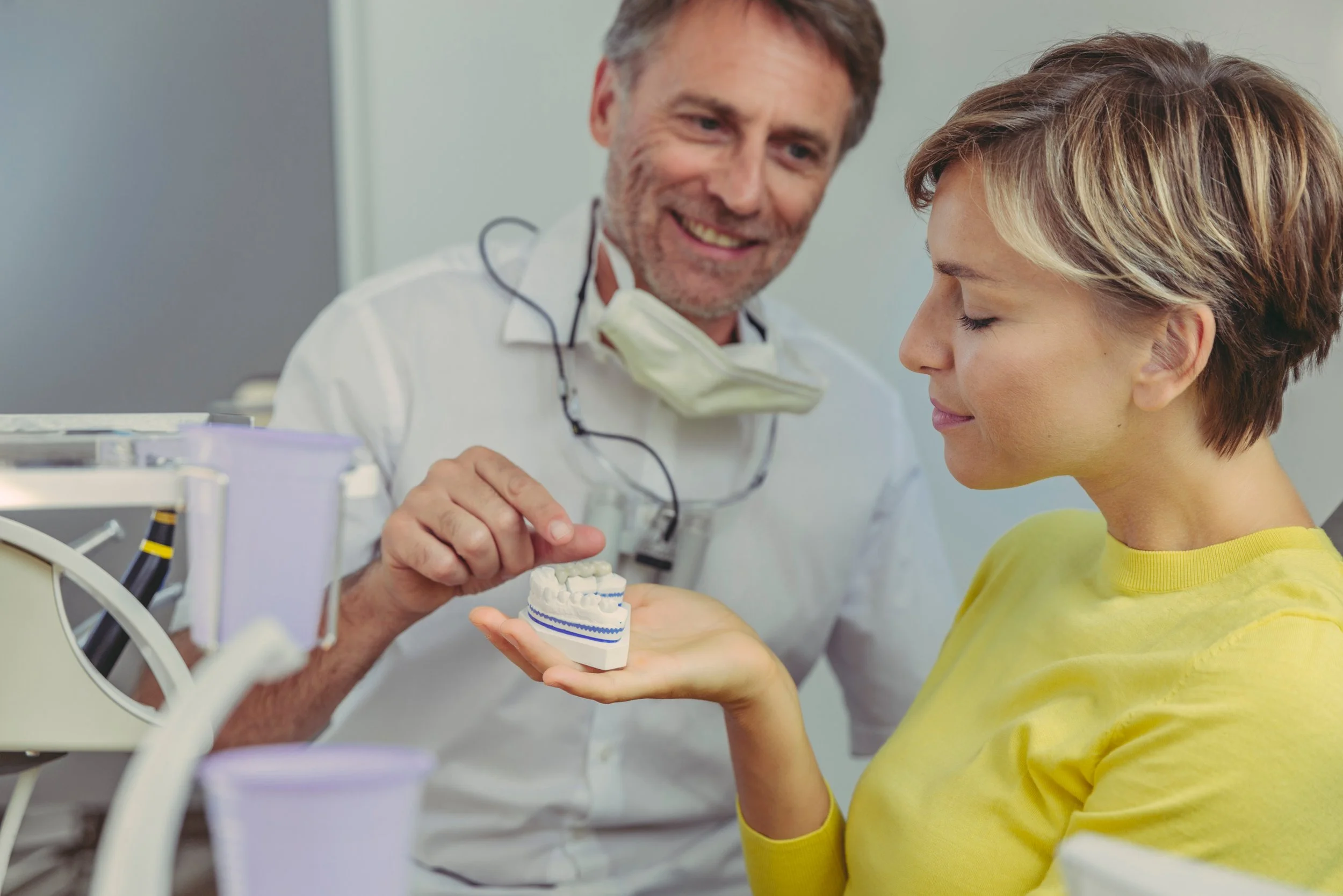 A dentist showing a dental model to a woman during a dental consultation.
