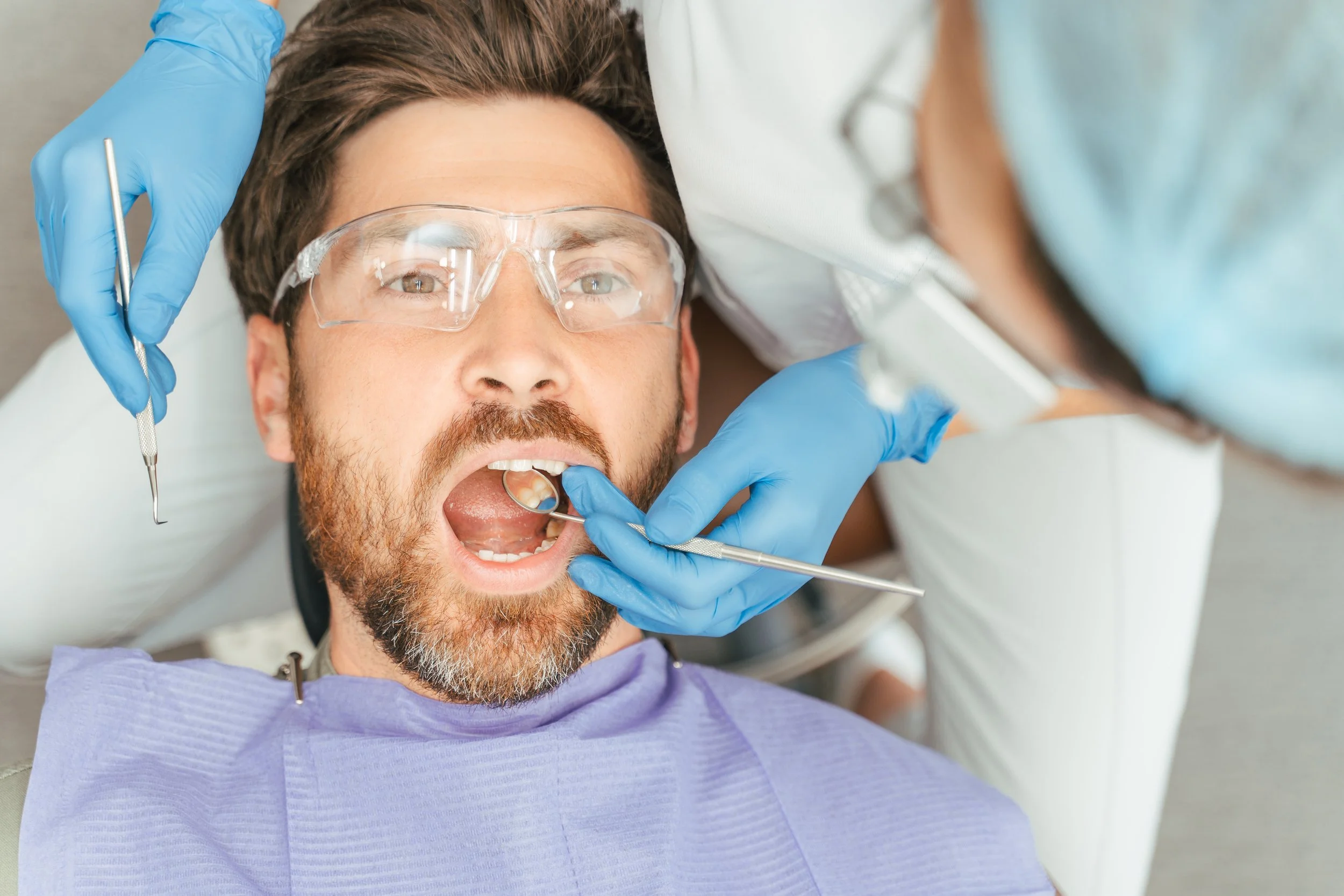 A man undergoing dental examination by a dentist.