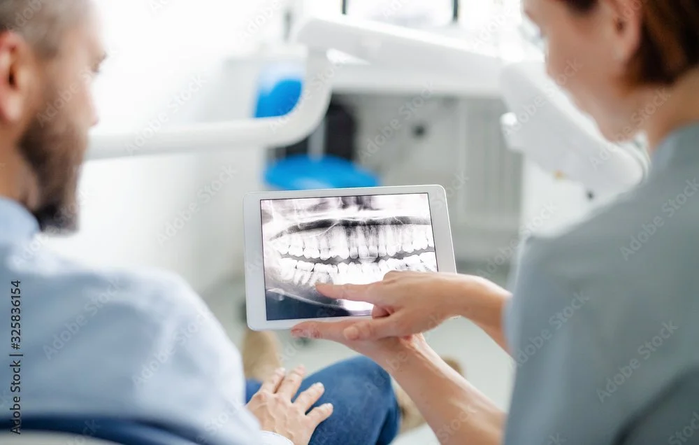 Modern house with wooden exterior in a mountainous landscape, surrounded by yellowish-green vegetation.
