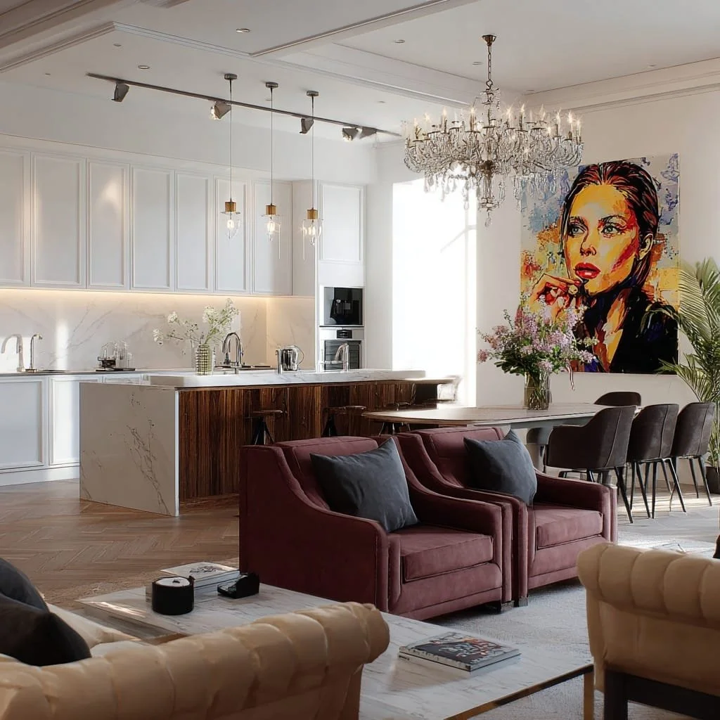 Sala de estar moderna con sillones color vino, mesa de centro de mármol con revistas, en el fondo cocina moderna con isla de mármol y gabinetes blancos, decoración con flores y un mural de retrato de mujer.