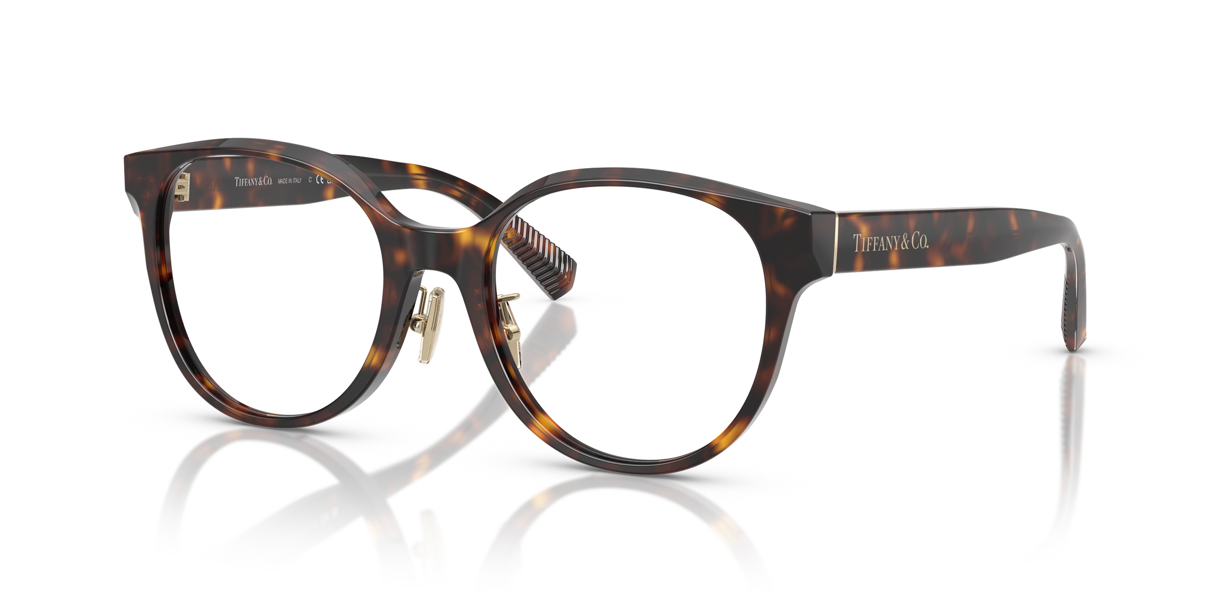 Tortoiseshell sunglasses with a rounded frame and gold accents, branded Tiffany & Co., against a white background with a reflective surface.
