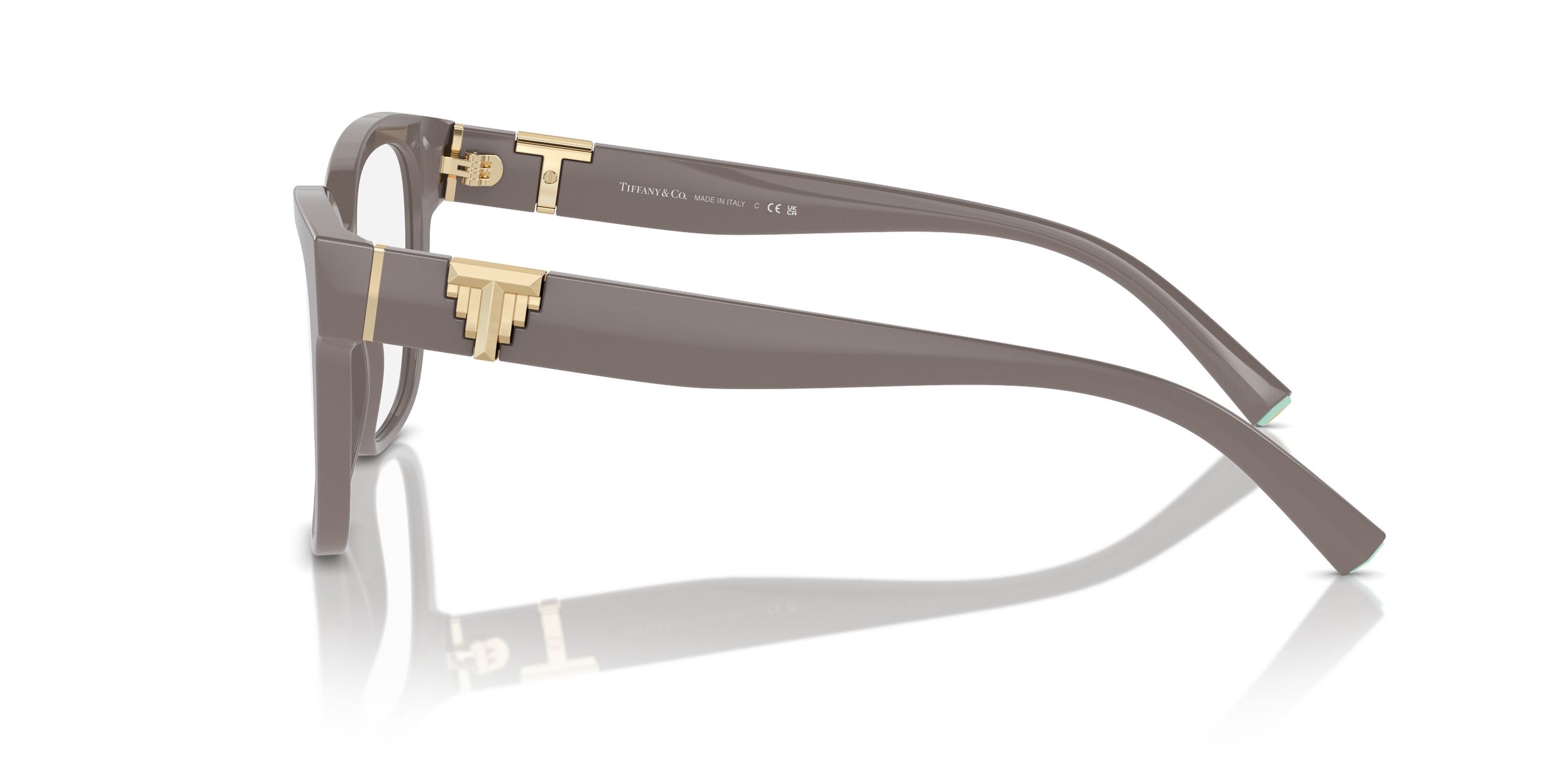 A fashionable pair of Tiffany designer glasses with gray frames and gold accents, resting on a reflective surface.