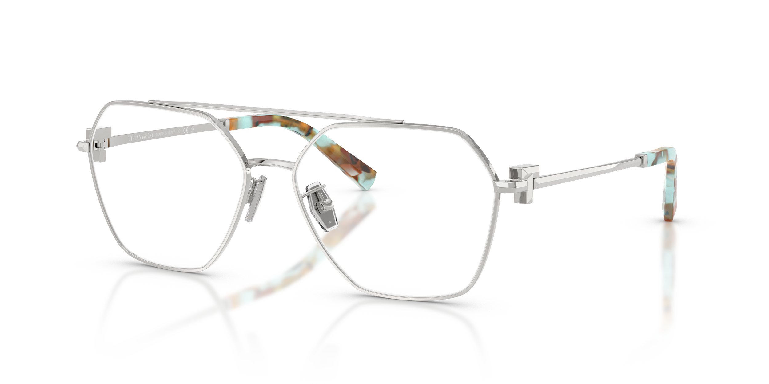 Stylish Tiffany designer eyeglasses with white metal frames and colorful tortoiseshell accents on the temples, reflected on a shiny surface.
