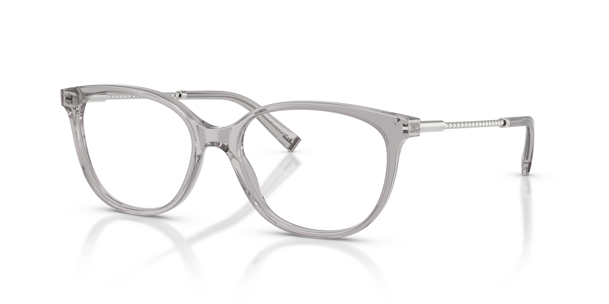 Clear, transparent Tiffany designer eyeglasses with round lenses and silver temples, reflecting on a white surface.