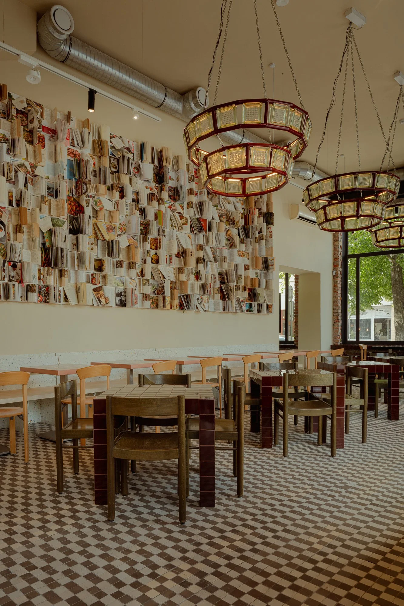 Interior of a cafe with a wall decorated with open books, hanging lights, and wooden tables and chairs.