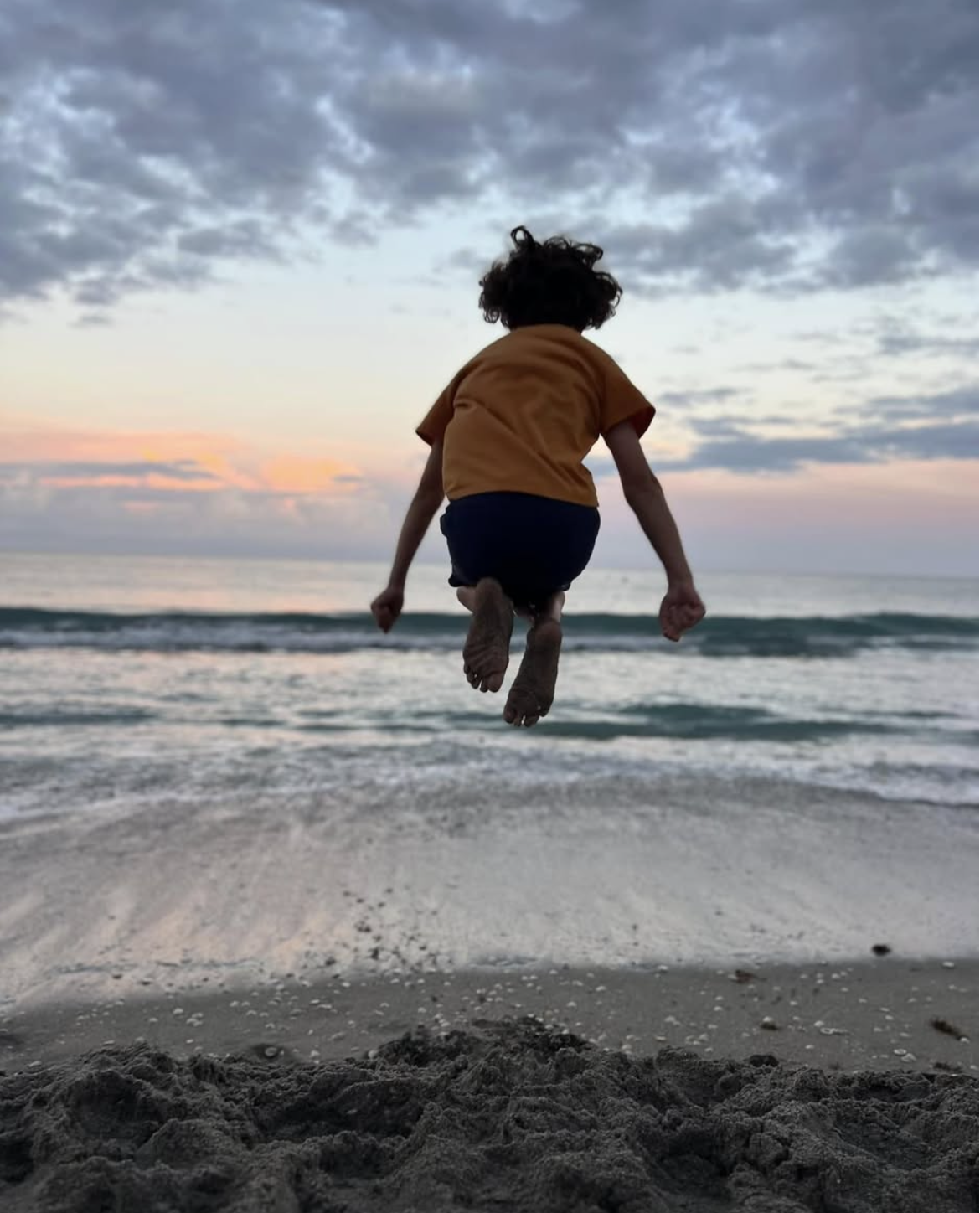 Photo of Whitehorn boy jumping near the Juno Beach ocean at sunset.