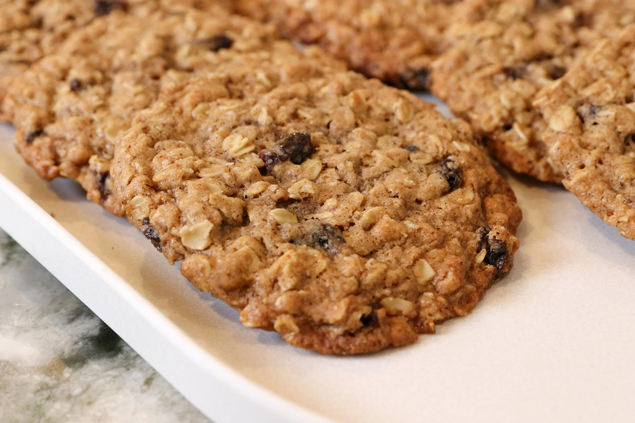 Close-up of homemade oatmeal raisin cookies on a white tray.