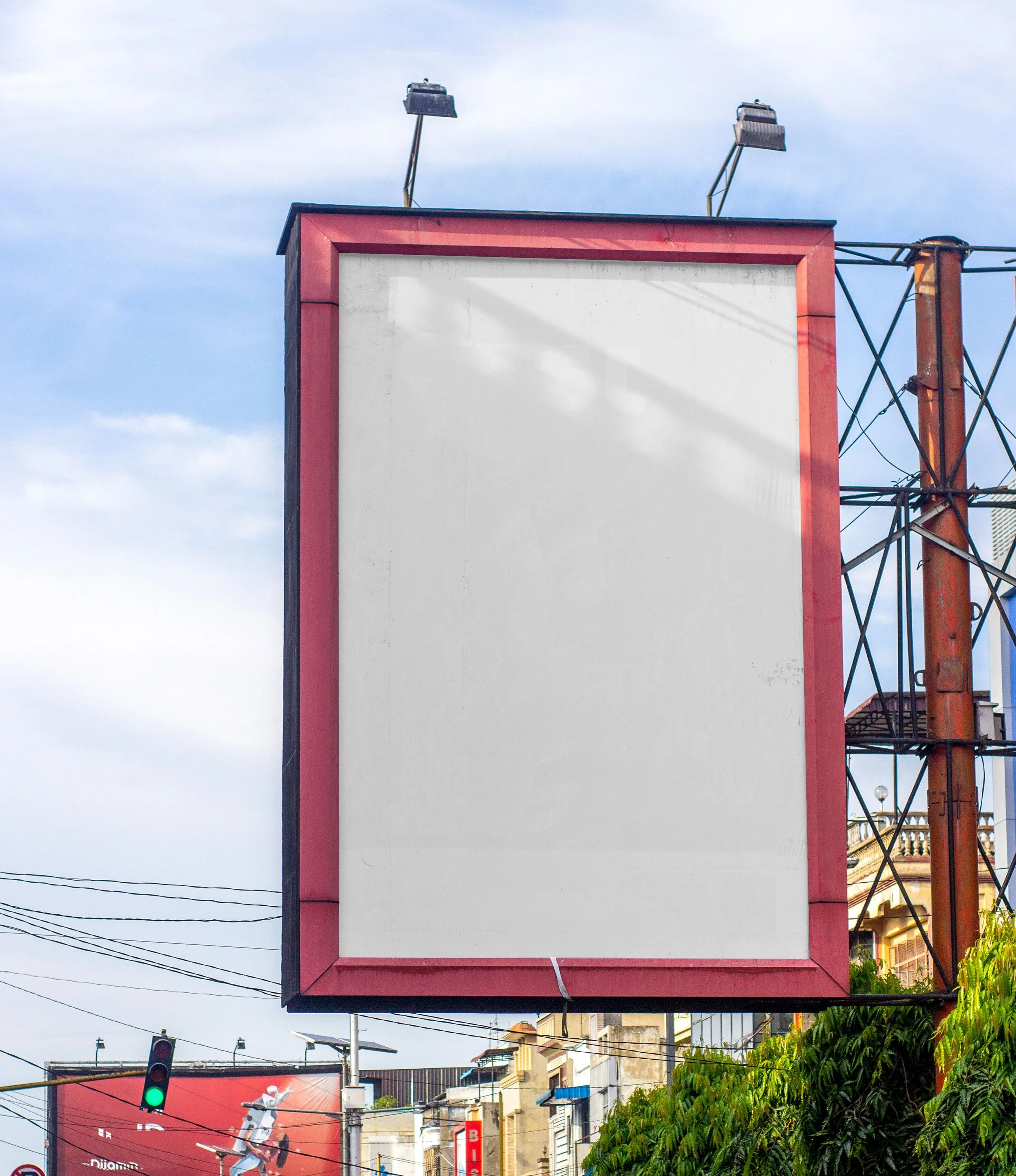 An empty billboard located around taller buildings and greenery