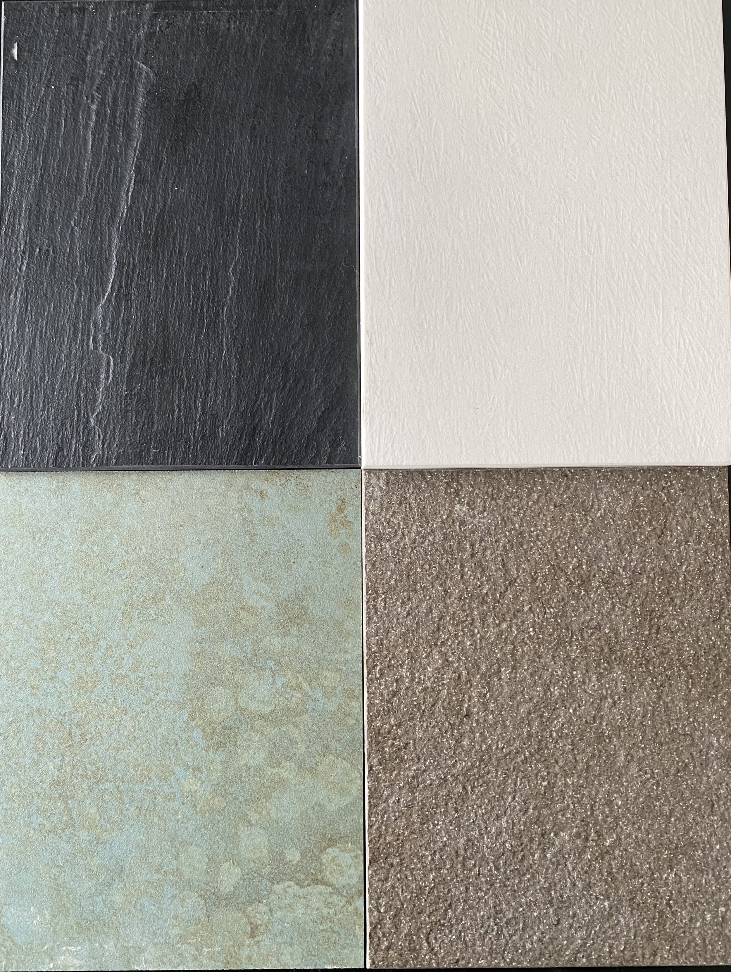 A collage of four different textured tiles in a 2x2 grid: top-left black slate tile, top-right white textured tile, bottom-left light greenish-blue tile with a mottled surface, bottom-right brownish textured tile.