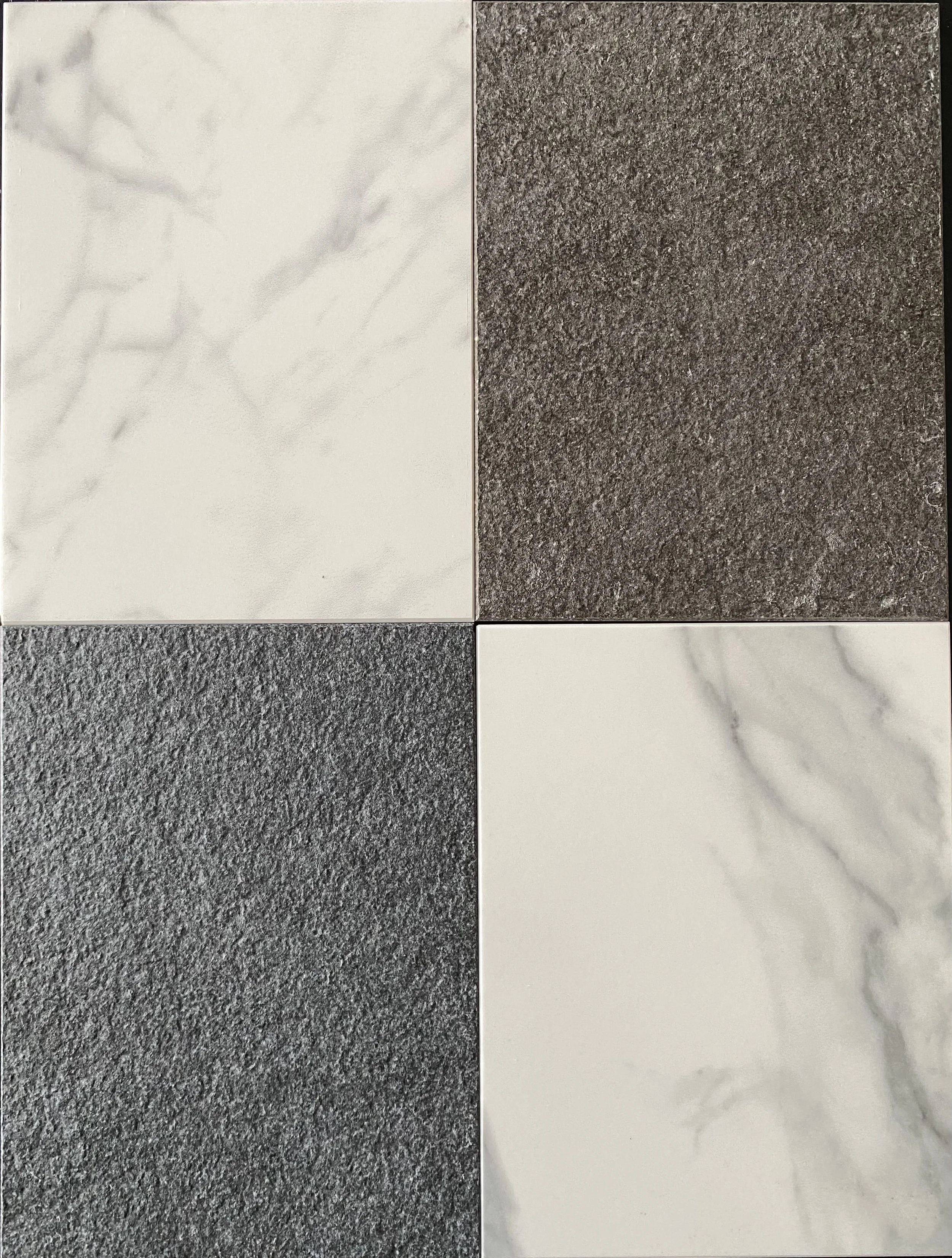 Four tile samples arranged in a 2x2 grid: top left is white marble with gray veining, top right is textured gray stone, bottom left is coarse dark gray stone, bottom right is white marble with gray veining.