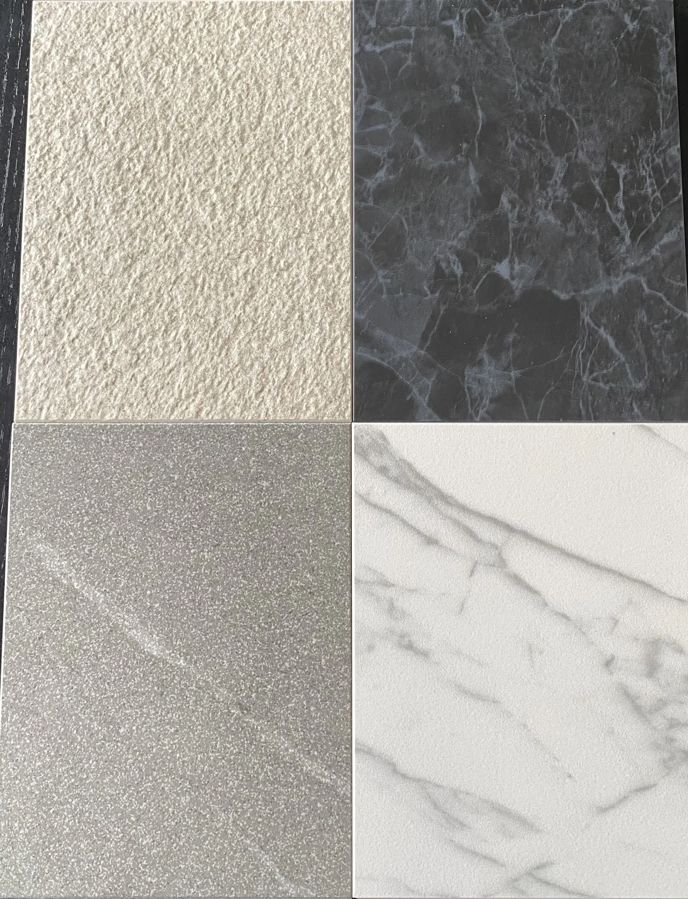 A collage of four different textured and patterned tiles: top left beige stucco, top right black marble, bottom left metallic with a slight shimmer, bottom right white marble with gray veins.