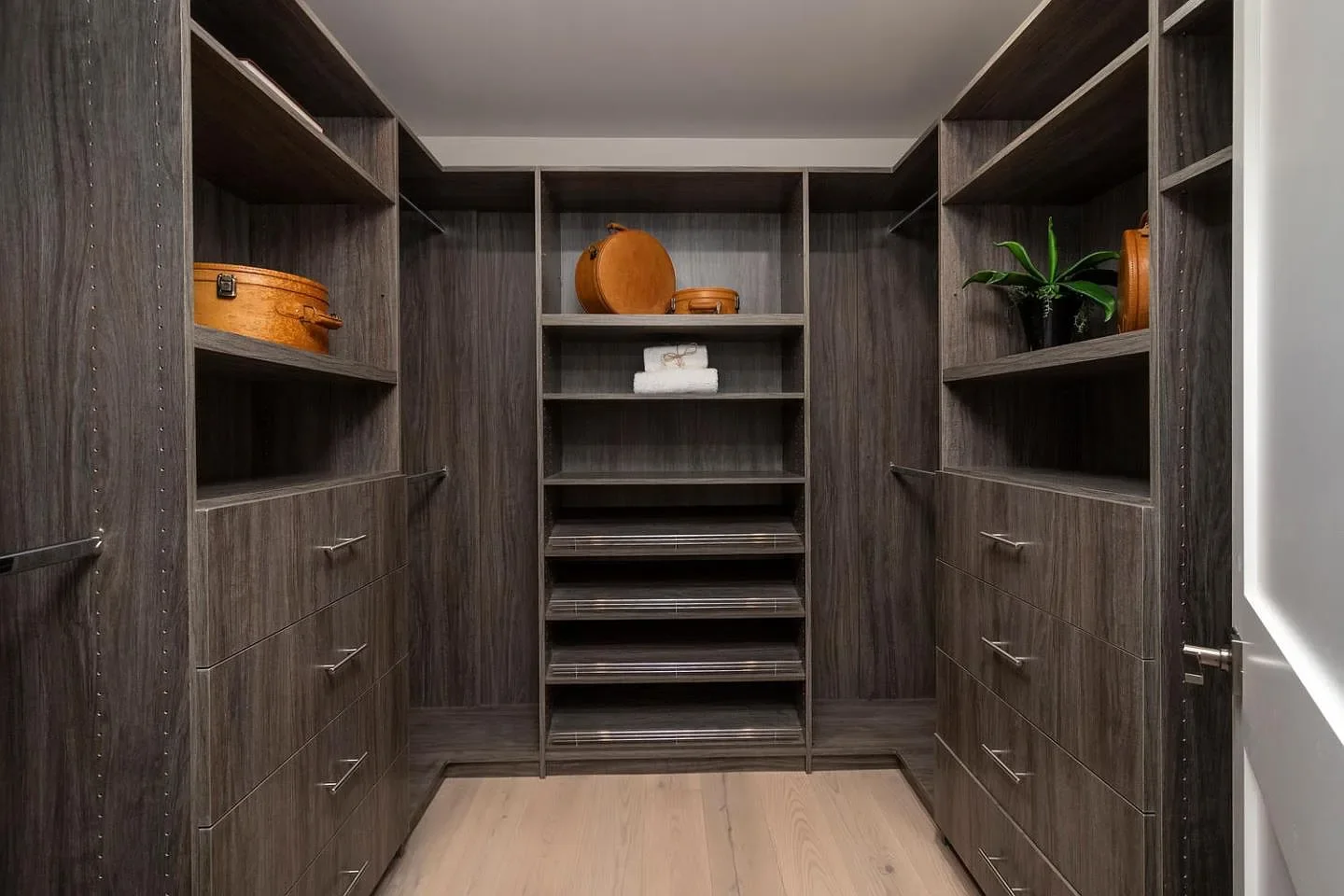 “Custom master closet in rich dark wood — elegant storage with a warm, tailored feel.